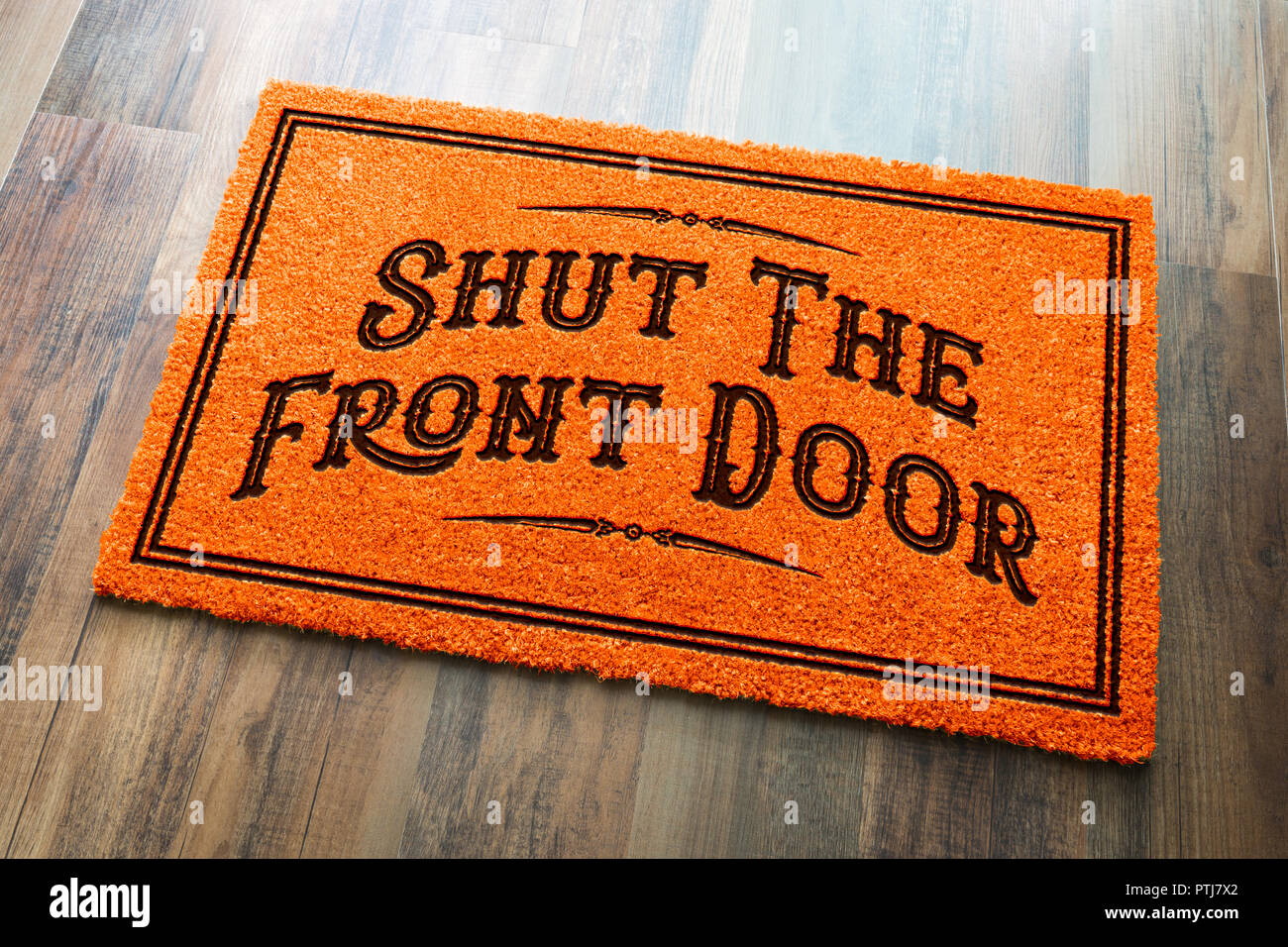 Shut The Front Door Halloween Orange Welcome Mat On Wood Floor Background. Stock Photo