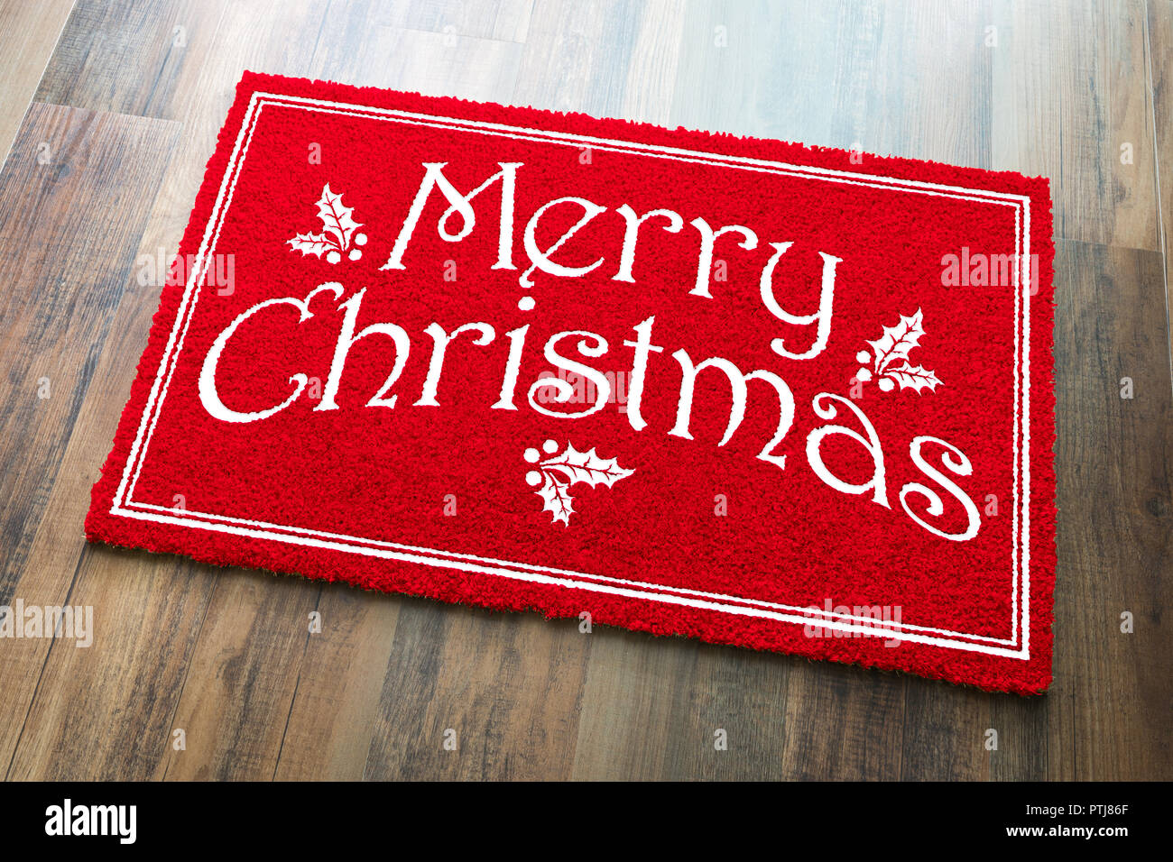 Merry Christmas Red Welcome Mat On Wood Floor Background. Stock Photo
