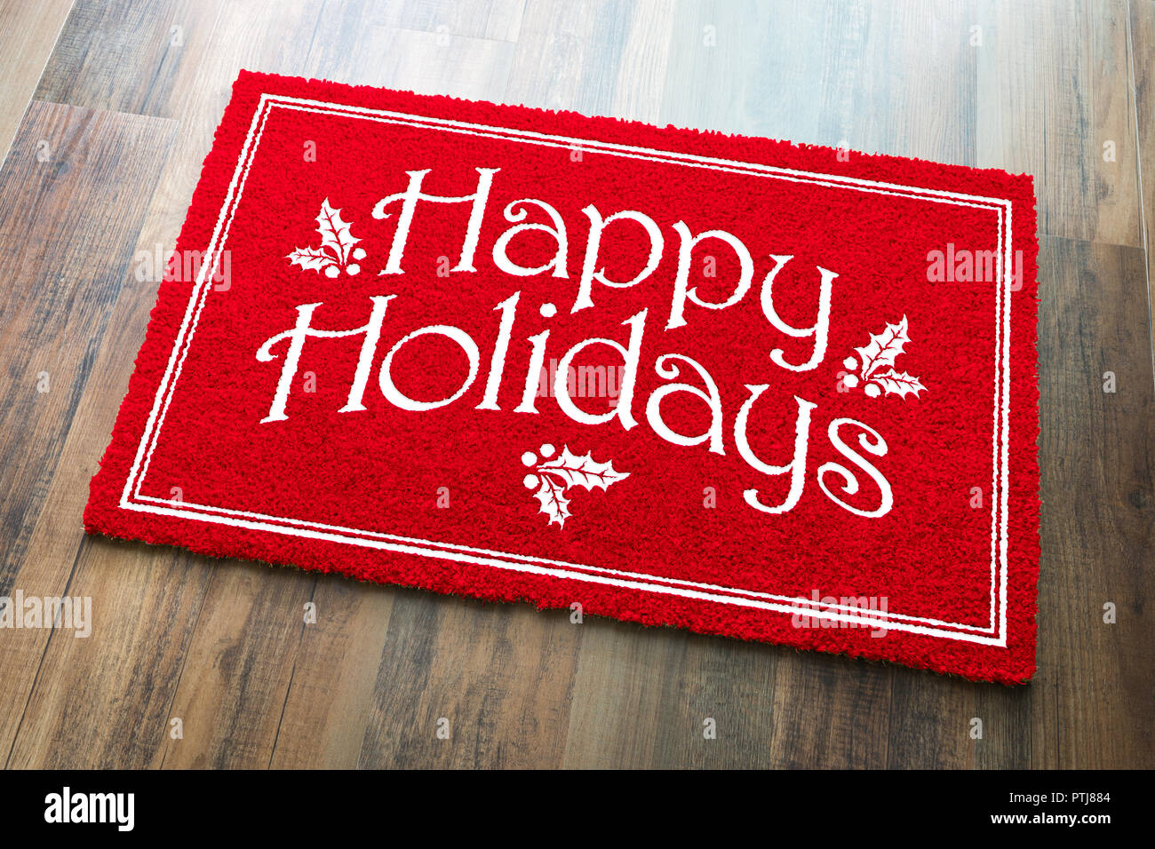 Happy Holidays Christmas Red Welcome Mat On Wood Floor Background. Stock Photo