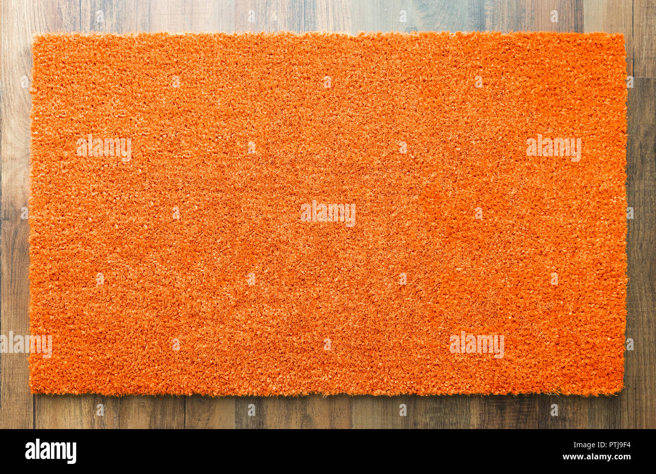 Blank Orange Welcome Mat On Wood Floor Background Ready For Your Own Text. Stock Photo