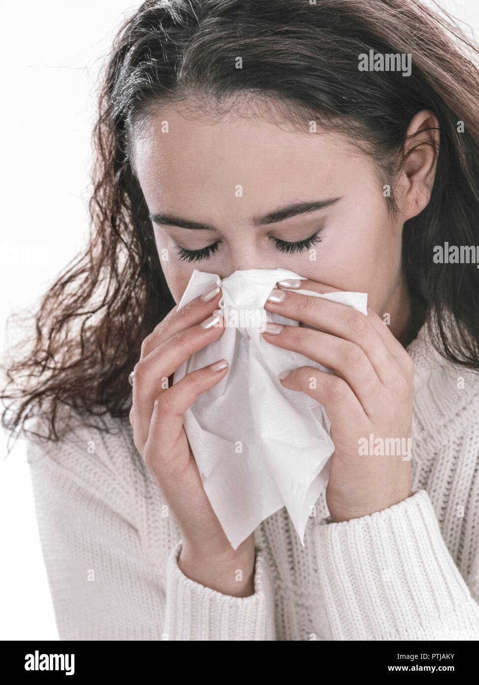 Erkaeltete junge Frau schnaeuzt in ein Papiertaschentuch (Modellfreigabe) Stock Photo