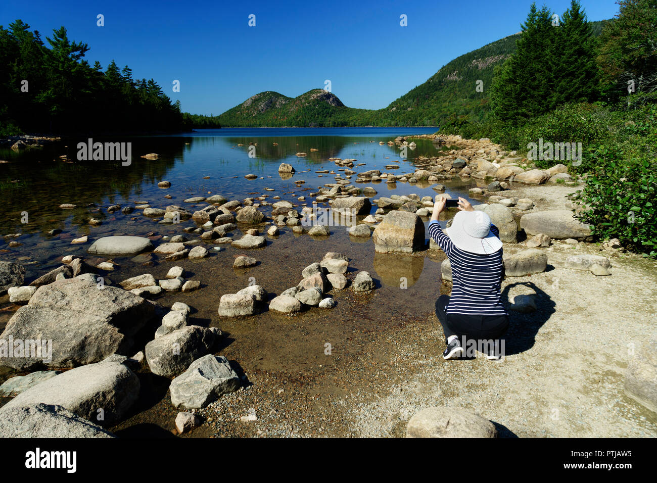 Woman taking a picture of Jordan Pond with her mobile phone. Acadia National Park, Maine, USA. Stock Photo