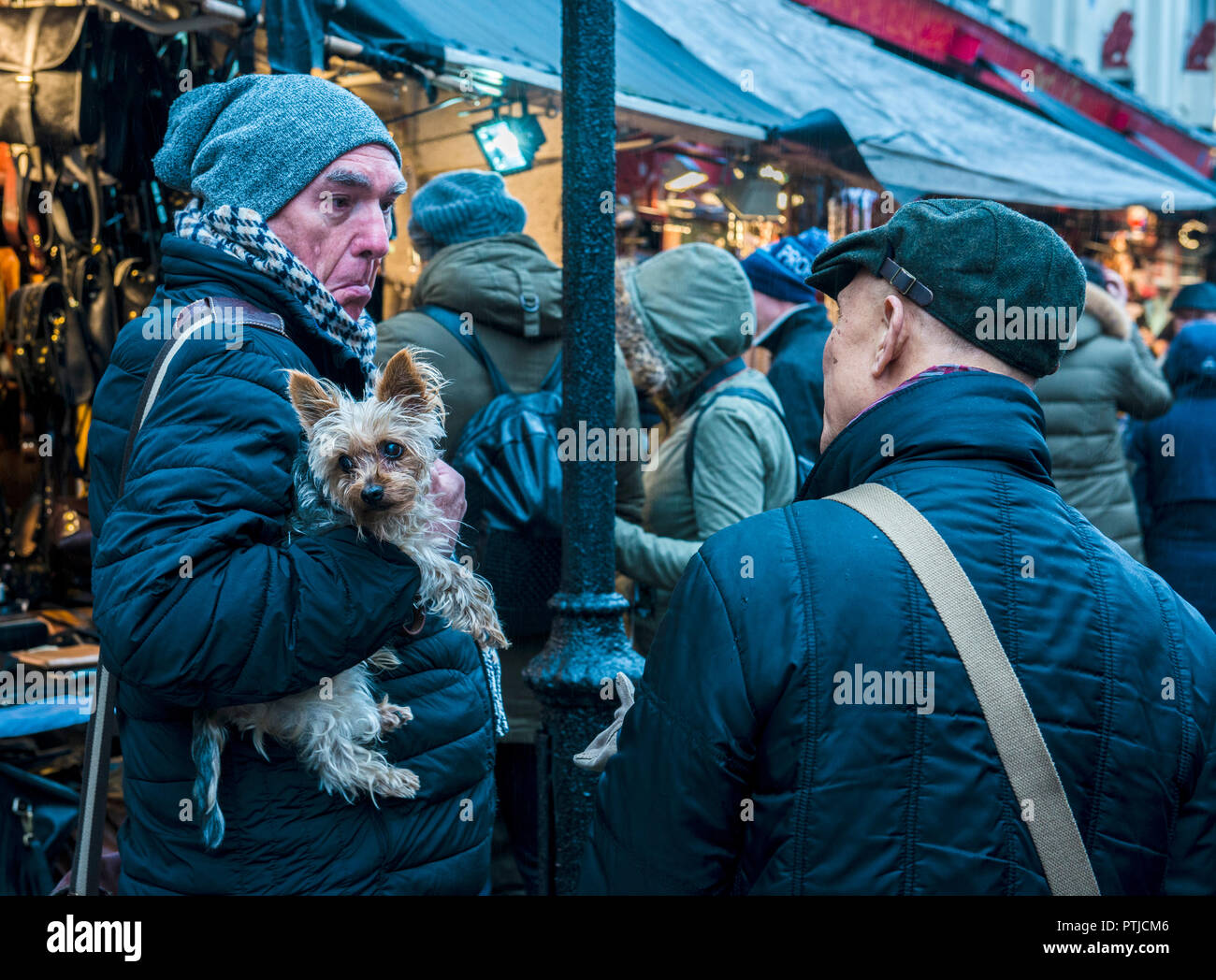 Two men face to face with one holding a dog. Stock Photo