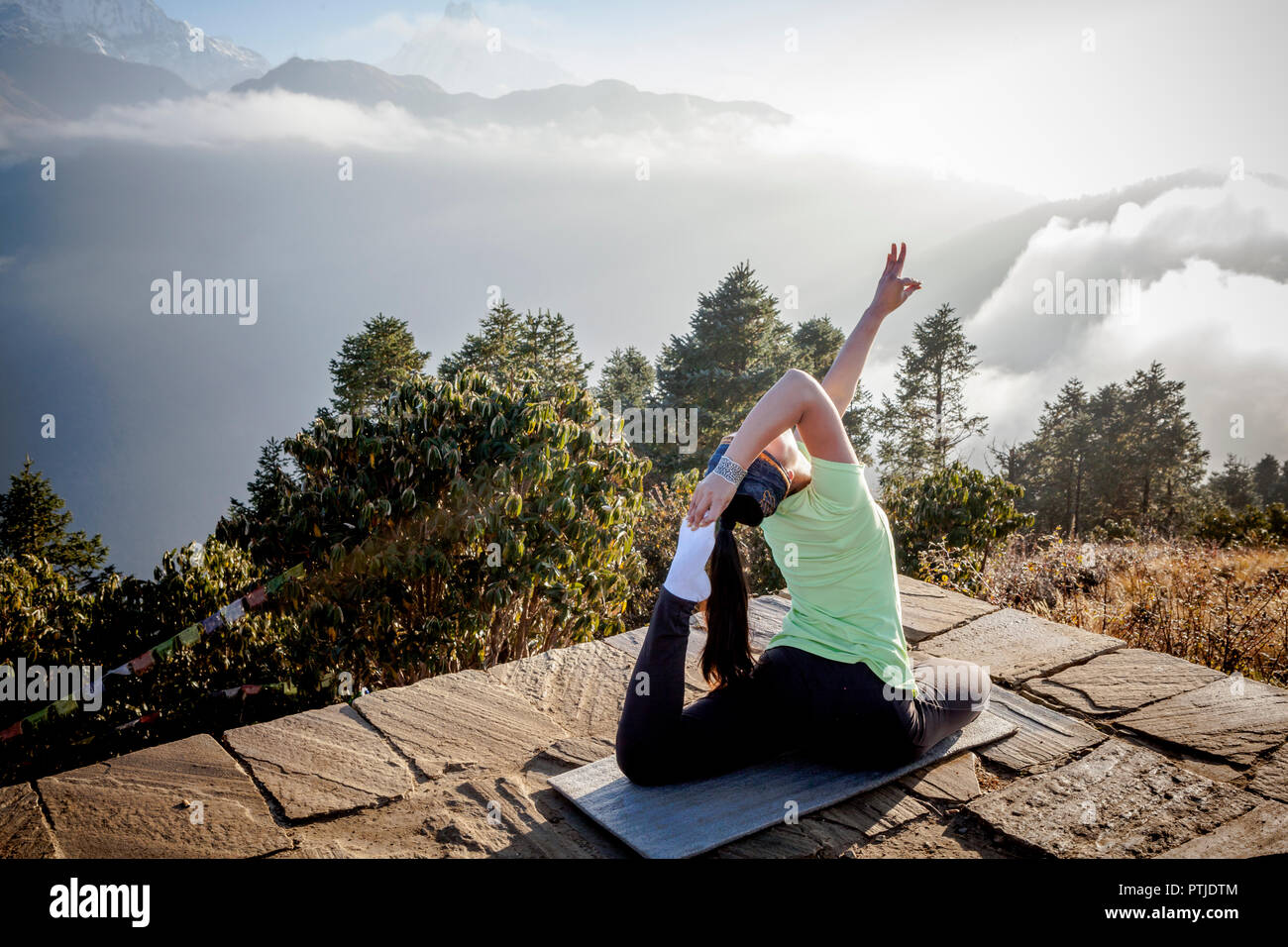 A women in a yoga pose during sunrise at Poon Hill in Nepal. Stock Photo