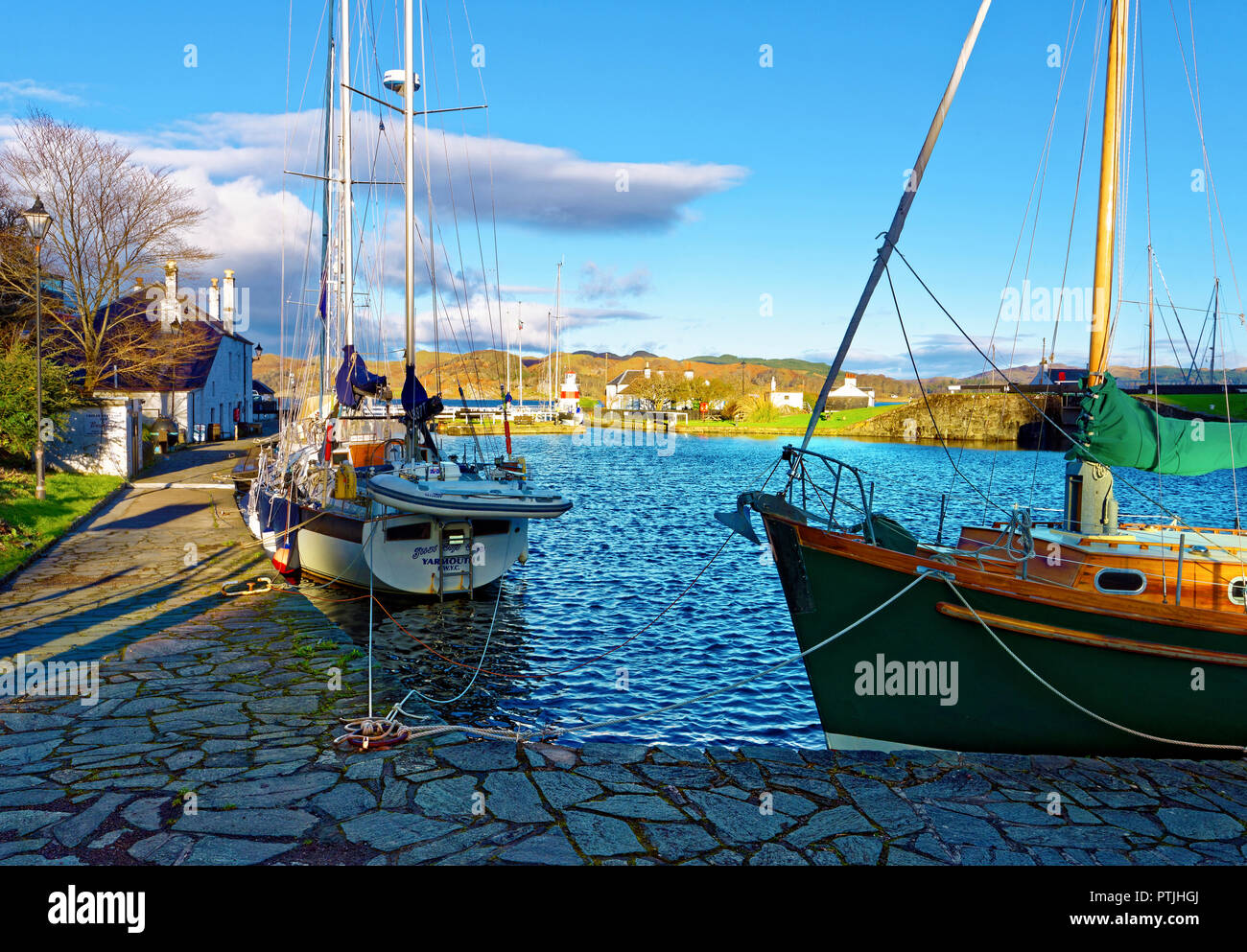 A sunny view of Crinan Harbour and the Crinan Canal along the Argyll and Bute coastline in the Scottish Highlands. Stock Photo