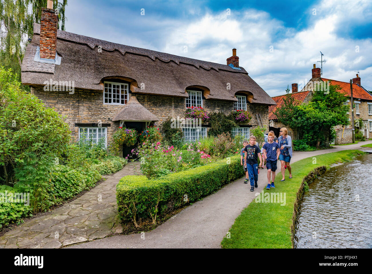 A family passing the famous thatched cottage at Thornton le Dale. Stock Photo