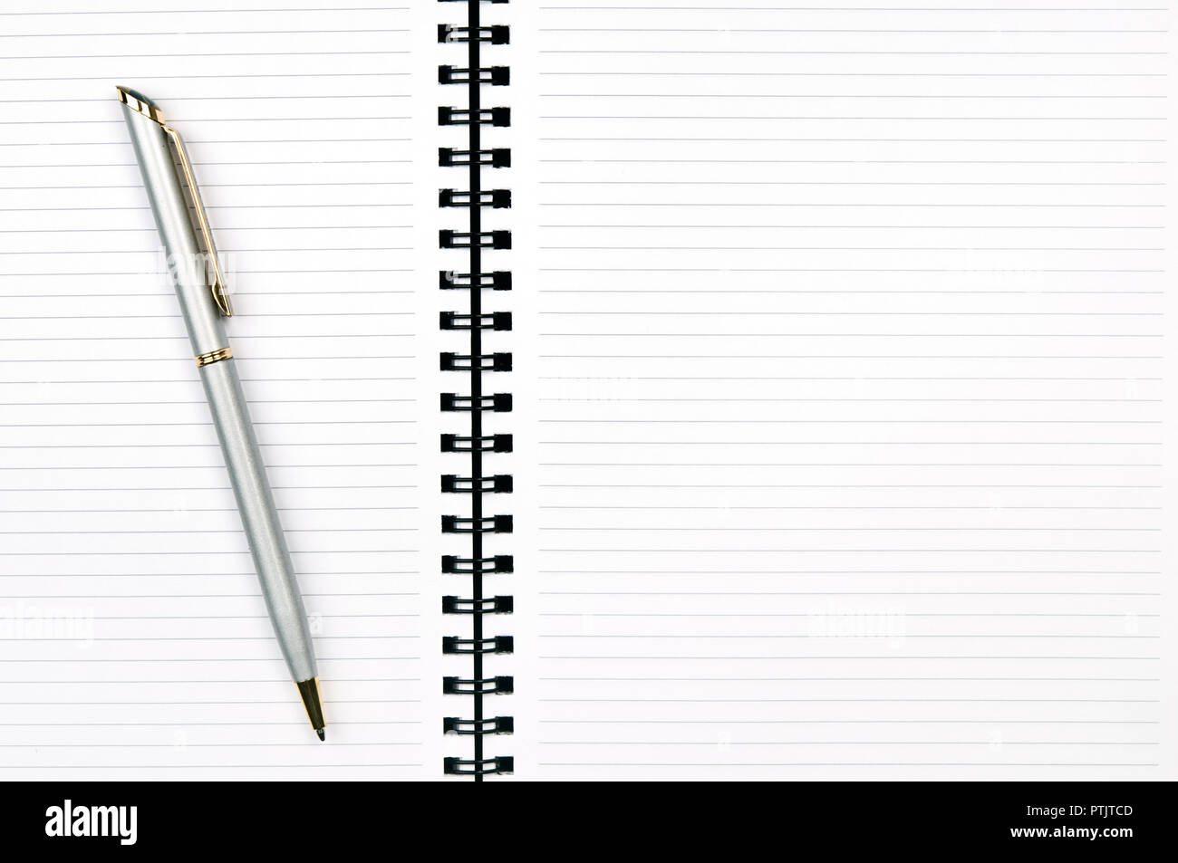 An open spiral notebook with blank pages and ballpoint pen. Stock Photo