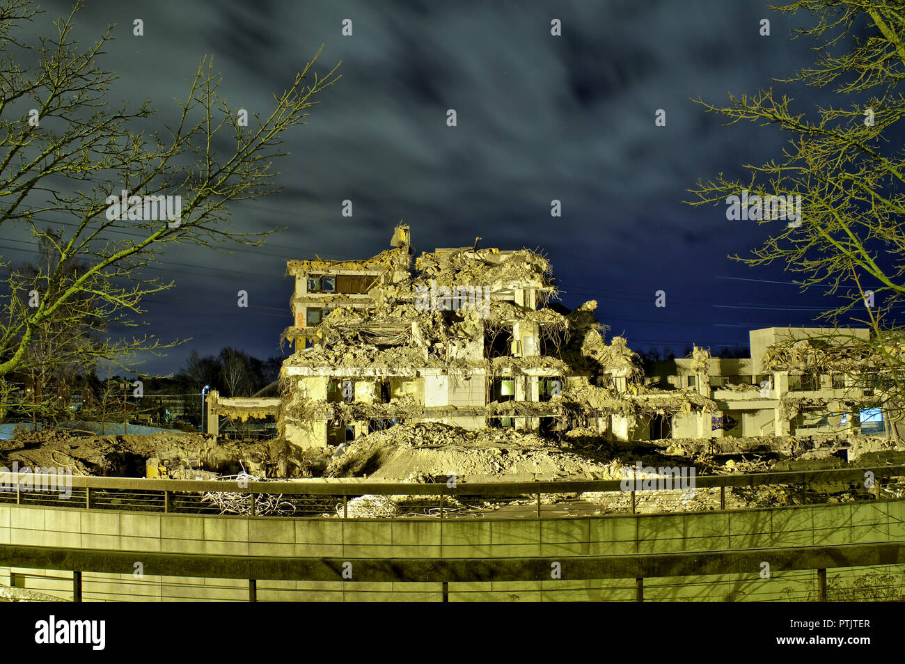 An apocalyptic view of ruins of an office building in the dark with no roof and walls. Interior visible through collapsed walls. Stock Photo
