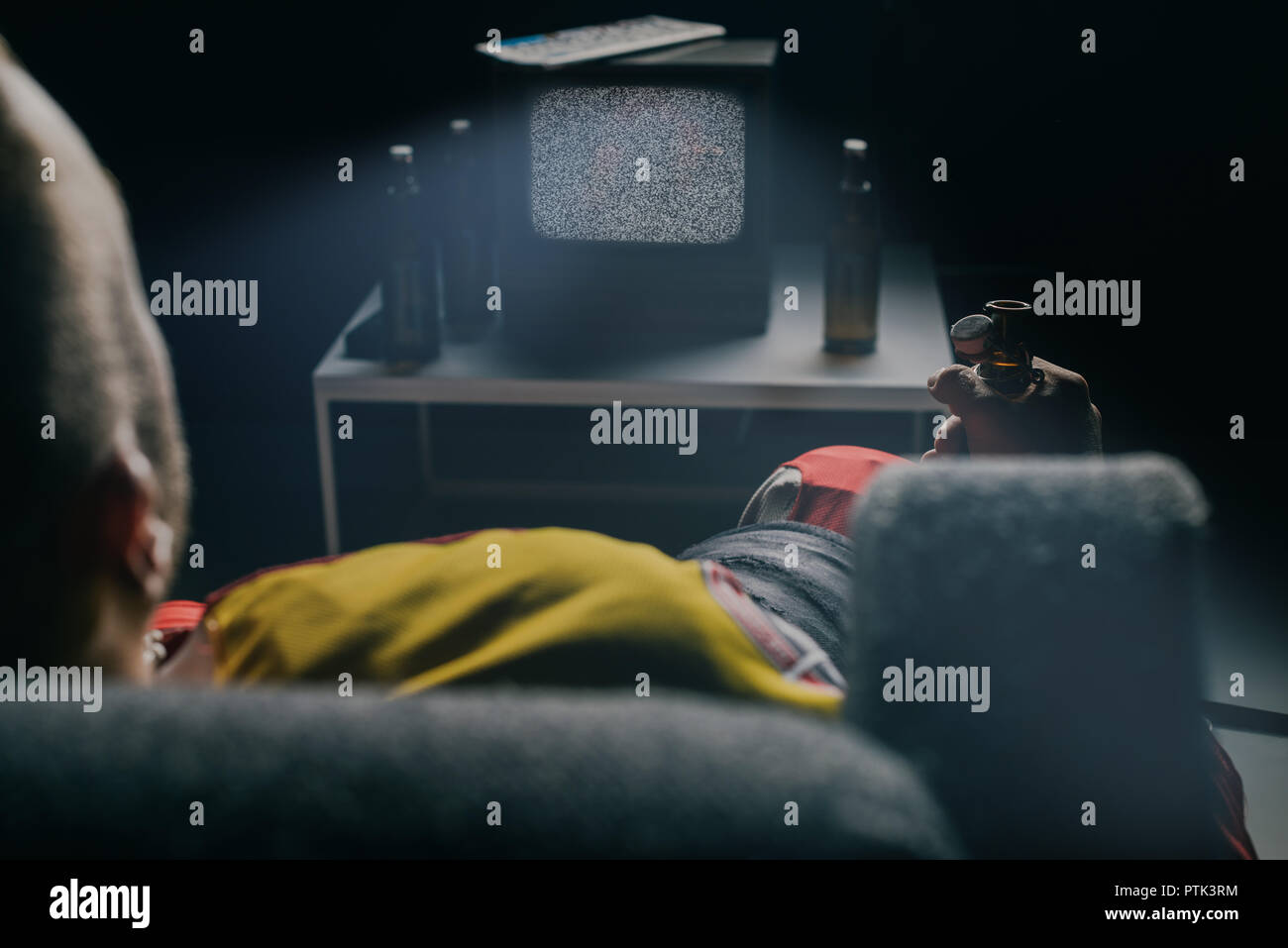 cropped shot of hockey player drinking beer and watching tv with static screen on black Stock Photo