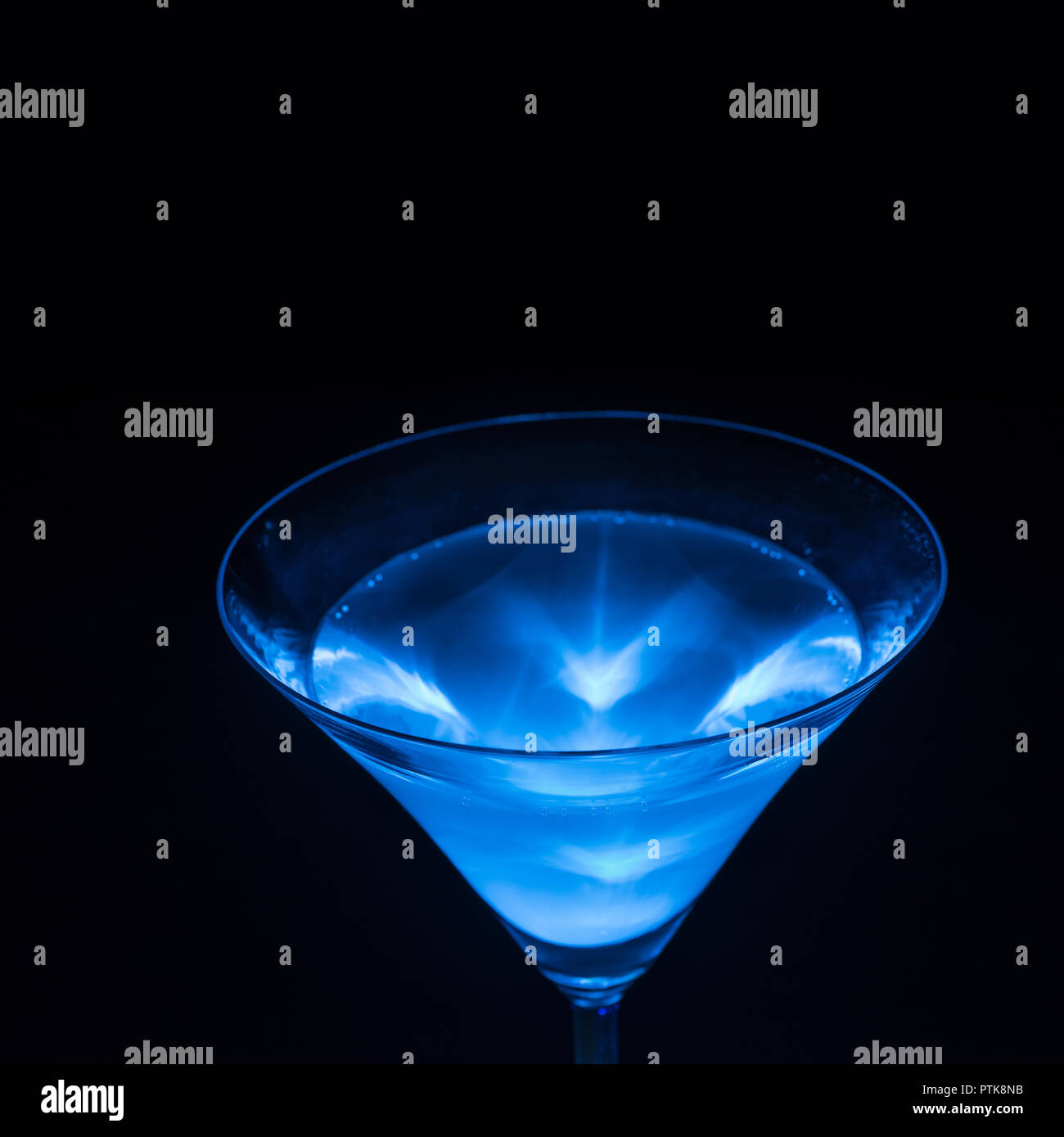 Glowing blue tonic water, quinine, as used in gin and tonic emmits light as visible when activated by ultraviolet A UV light 365 nm Stock Photo