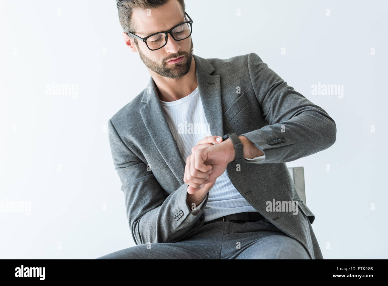 handsome bearded businessman in gray suit looking at watch, isolated on white Stock Photo