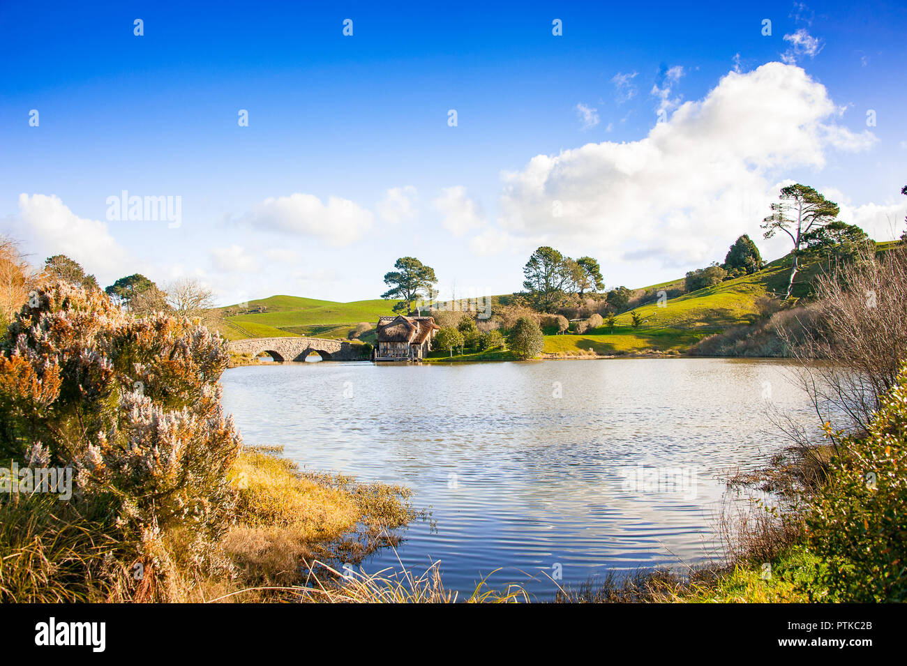 Matamata, New Zealand: Hobbiton movie set created to film Lord of the Rings and The Hobbit. View across lake to old mill and bridge. Stock Photo