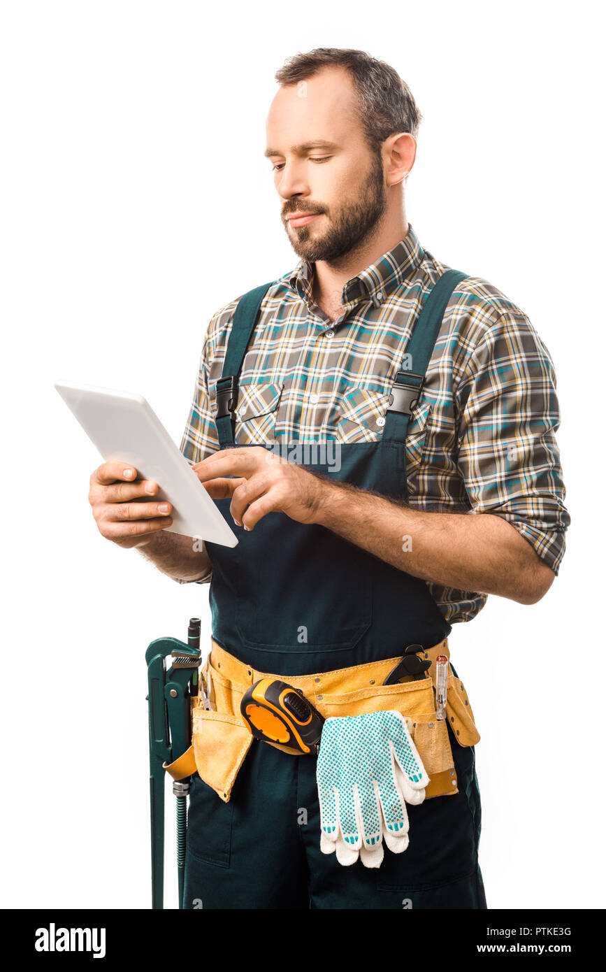handsome plumber with tool belt using tablet isolated on white Stock Photo