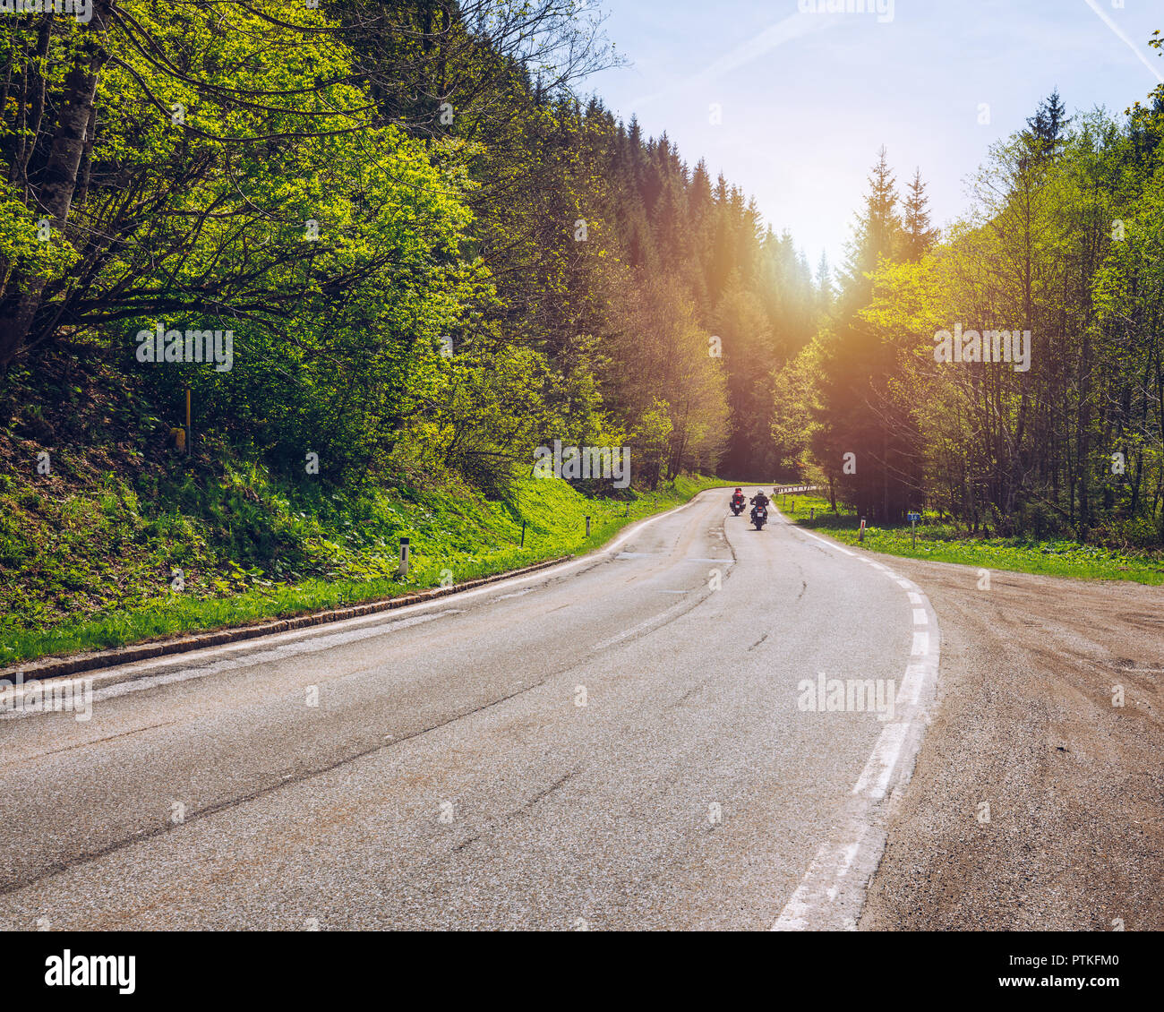 Bikers on mountainous highway, biker on the road in sunset light riding on curve road pass across Alpine mountains, extreme lifestyle, freedom concept Stock Photo