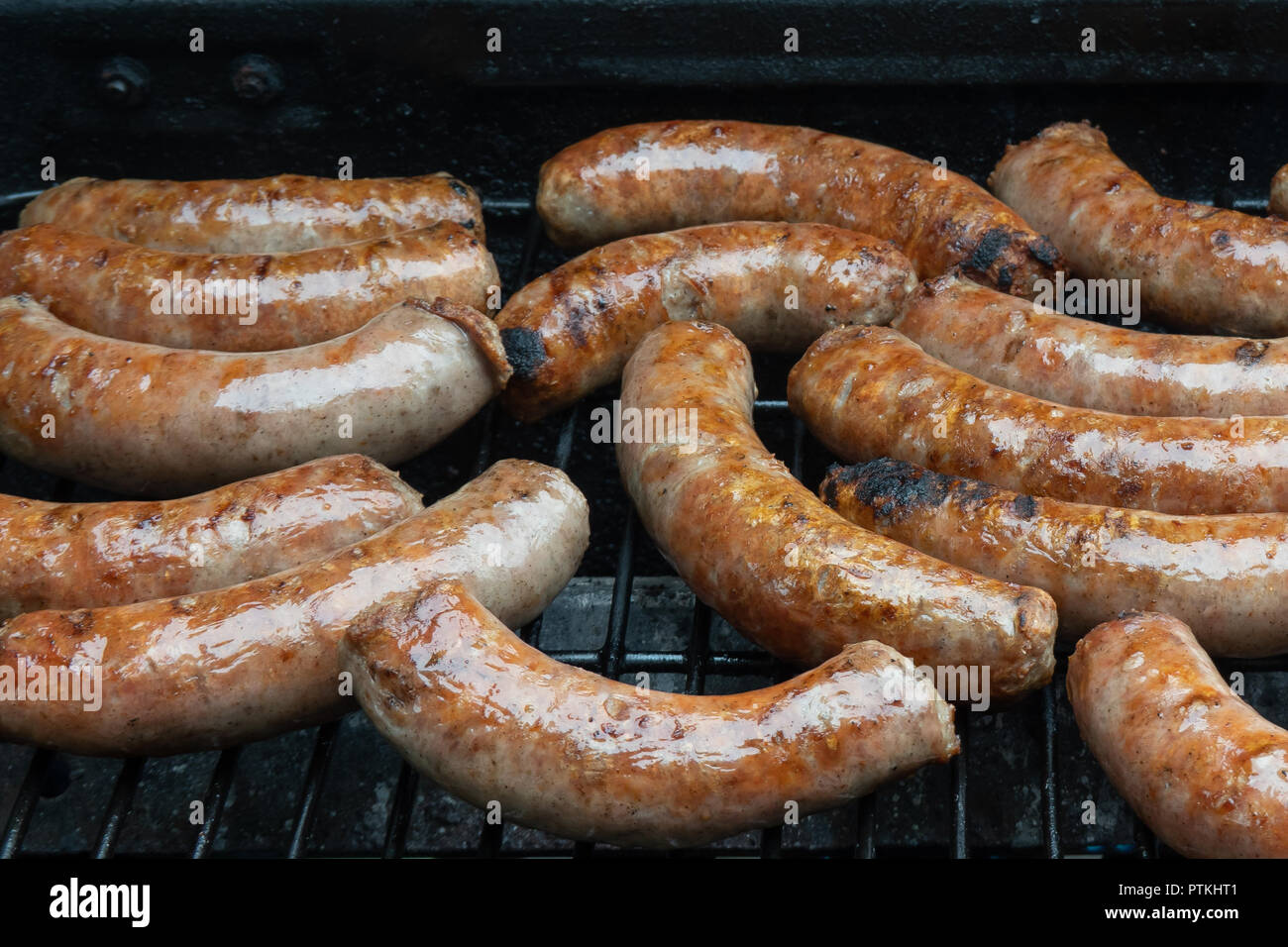 Pieces of pork sausage cooking on a gas grill. Stock Photo