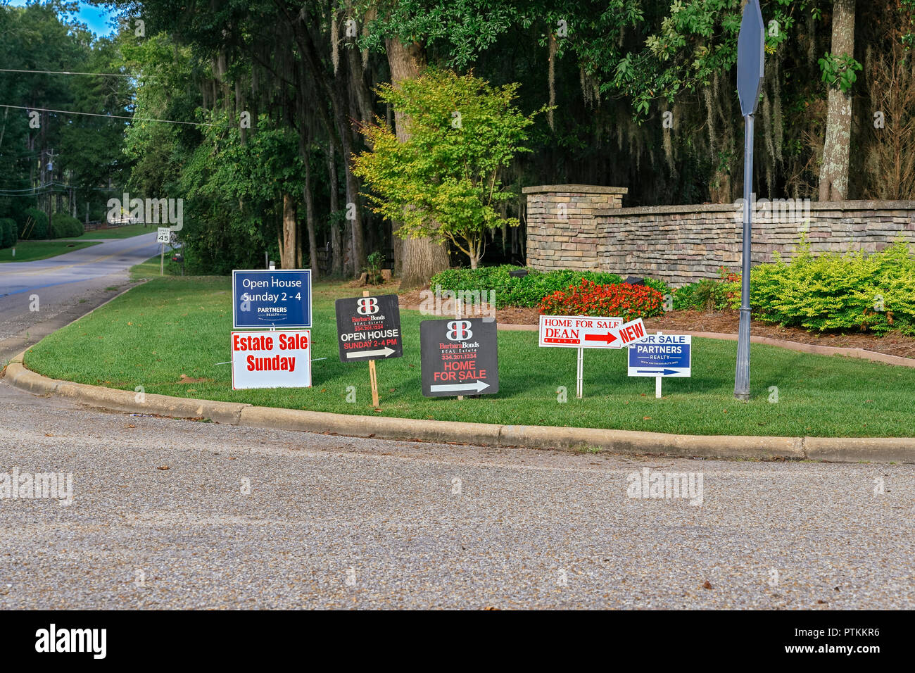 Row of real estate for sale signs along the road leading into a suburban residential neighborhood in Montgomery Alabama, USA. Stock Photo