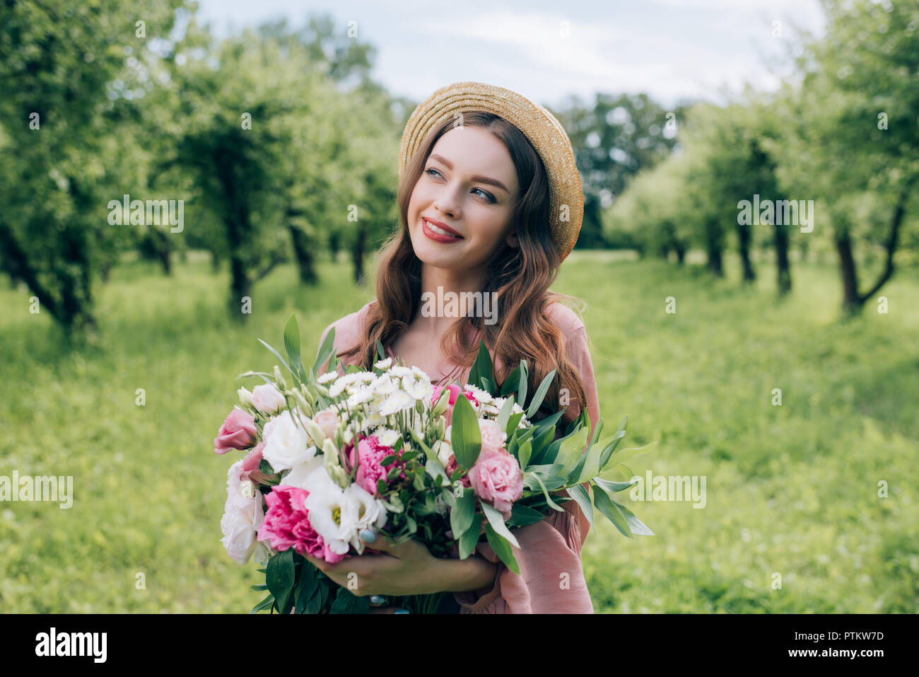 portrait of beautiful smiling woman in hat with bouquet of flowers ...