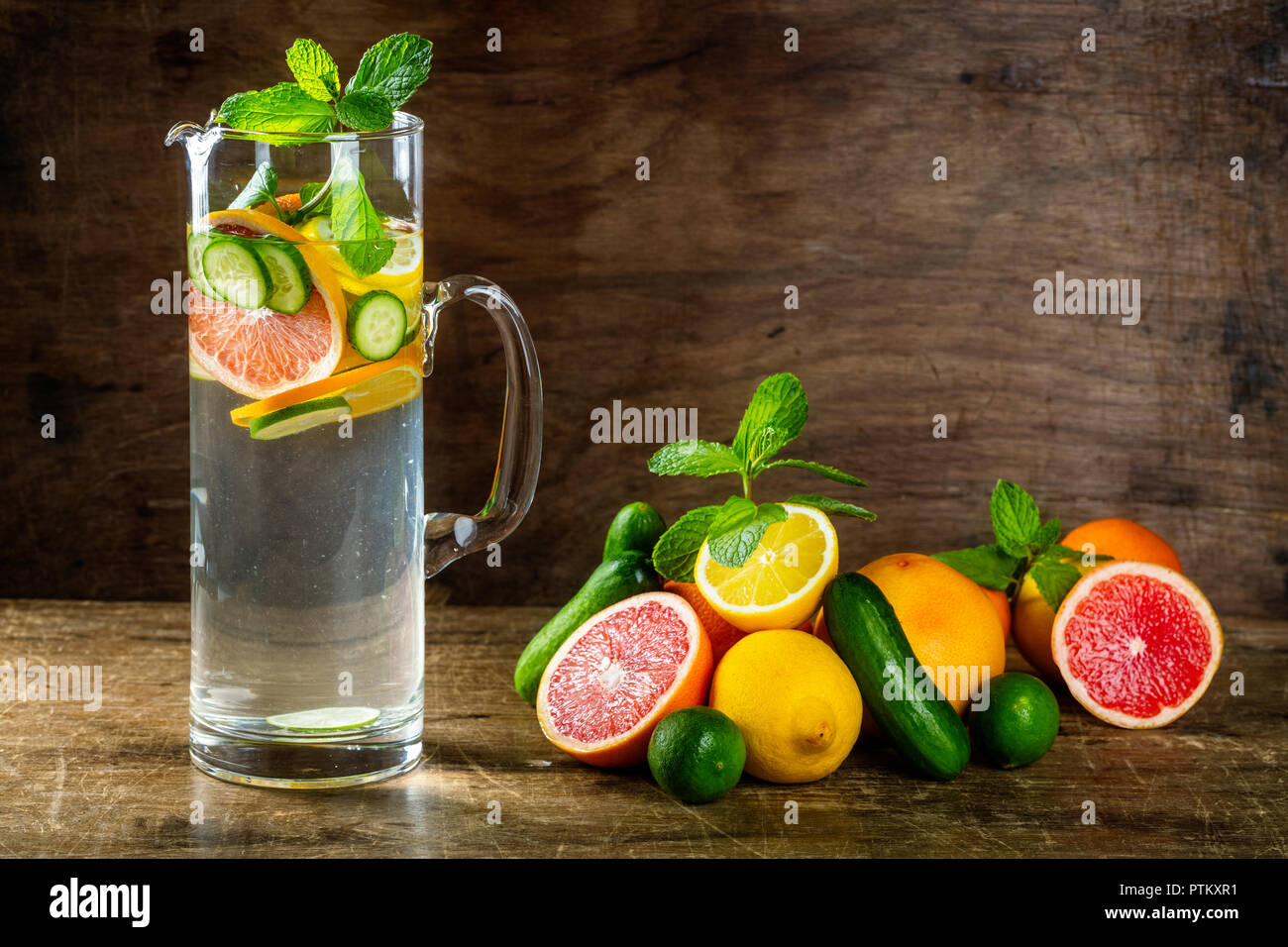 Water Sassy with lemon, grapefruit, orange, mint, cucumber and ginger, selective focus, on wooden background Stock Photo