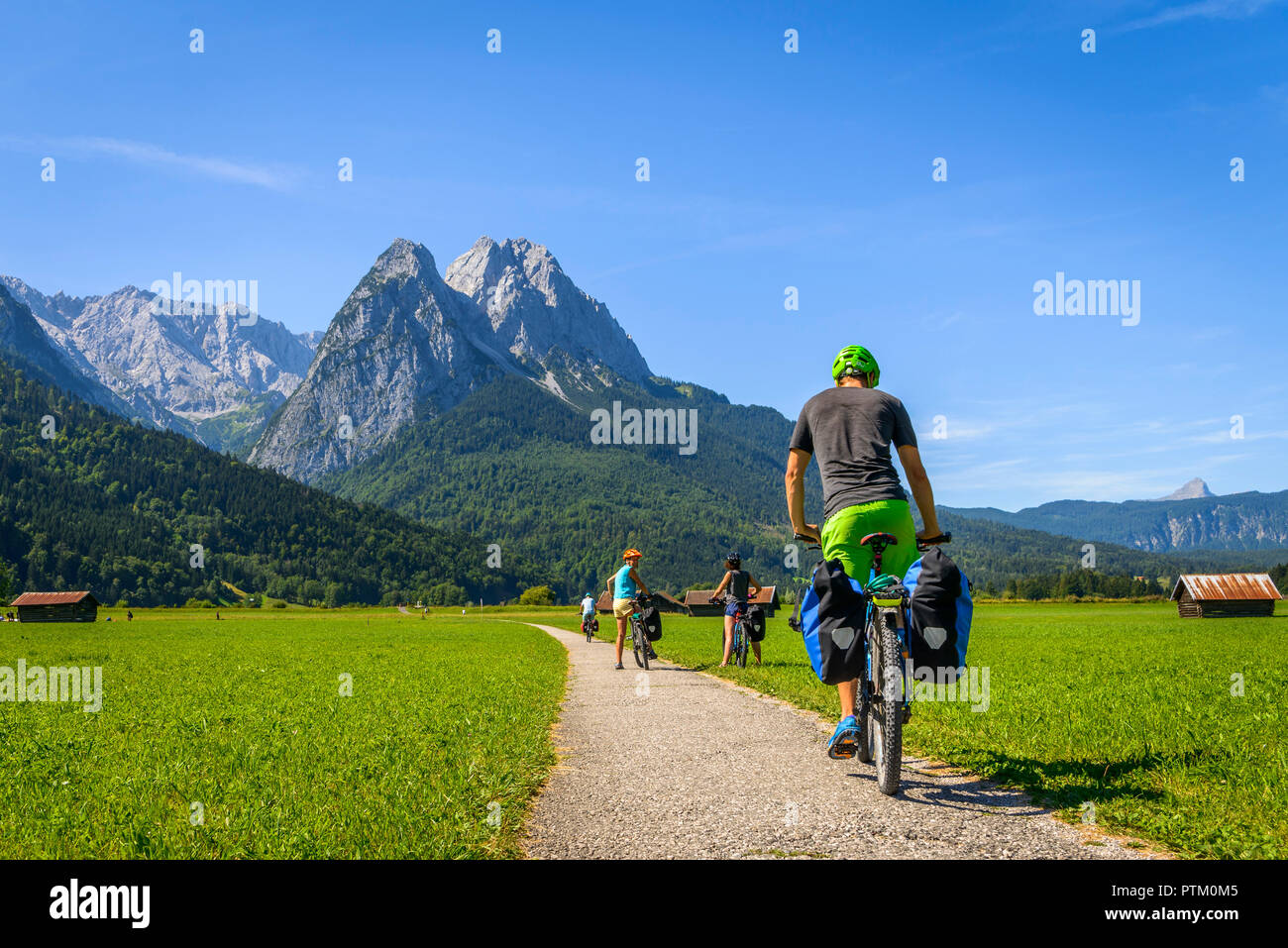 Cyclist on bike tour riding on bike path on his mountain bike, in the back Zugspitze, Tegernauweg, near Grainau Stock Photo