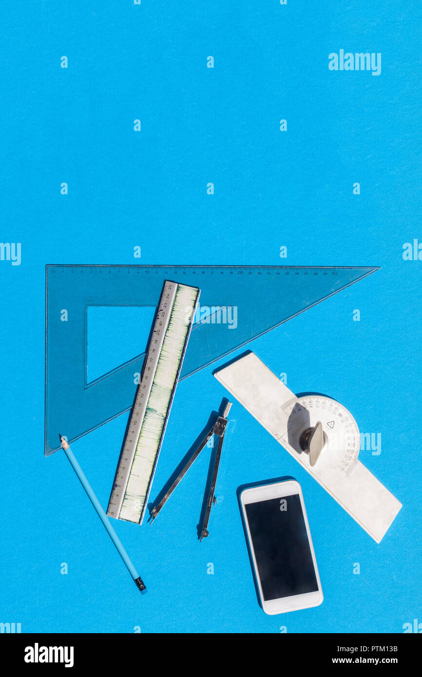 Geometry set with compass, rulers, pencil and protractor on blue