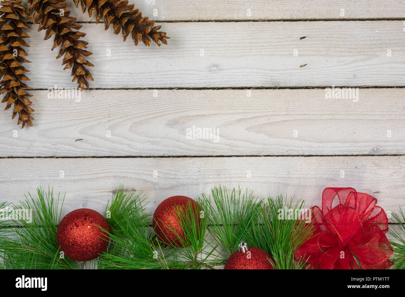 A border of white pine boughs , three red ornaments, and a red bow