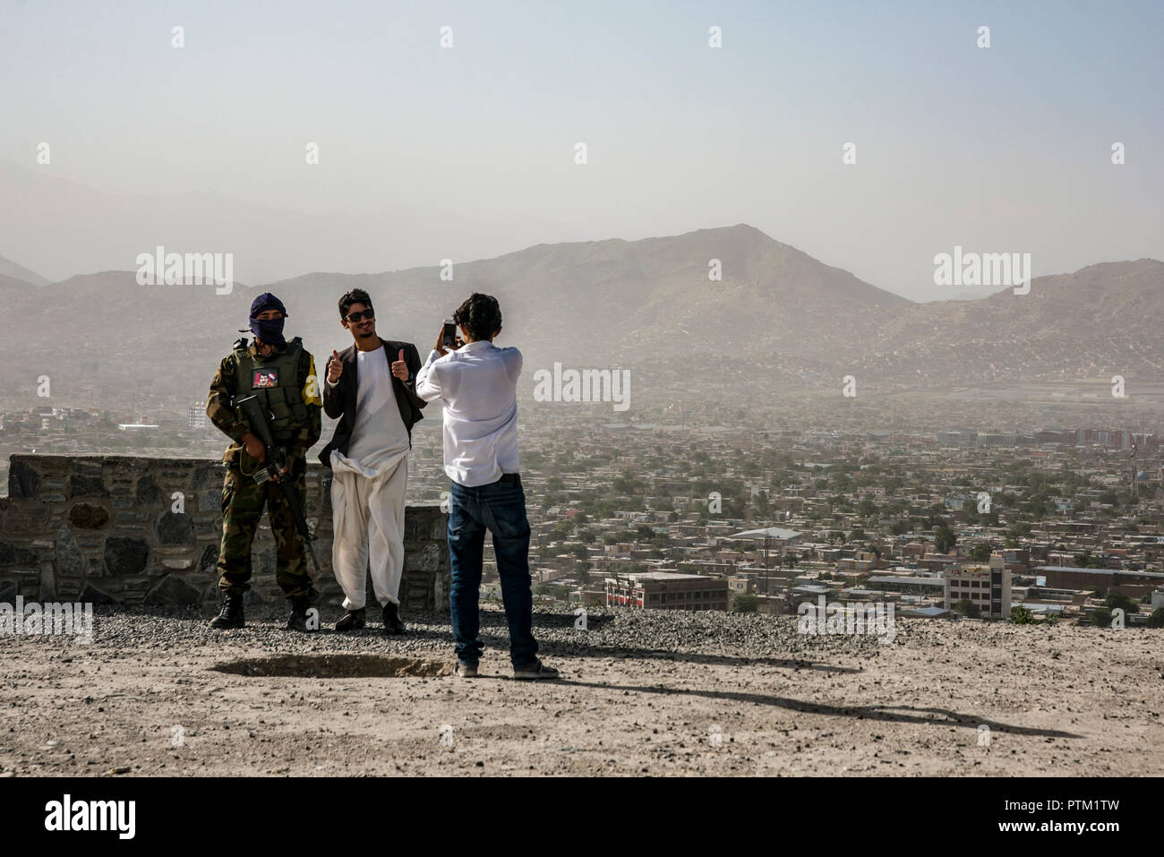 Local guys take a picture with a soldier at the top of swimming pool hill in Kabul in Afghanistan. Stock Photo