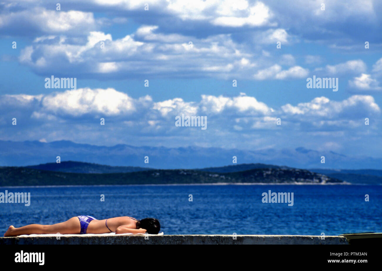 Woman laying on wall sun bathing,Dugi Otok, Croatia Stock Photo
