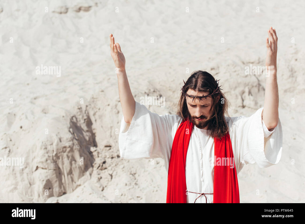 Jesus in robe, red sash and crown of thorns holding rosary and standing  with open arms against blue Stock Photo by LightFieldStudios