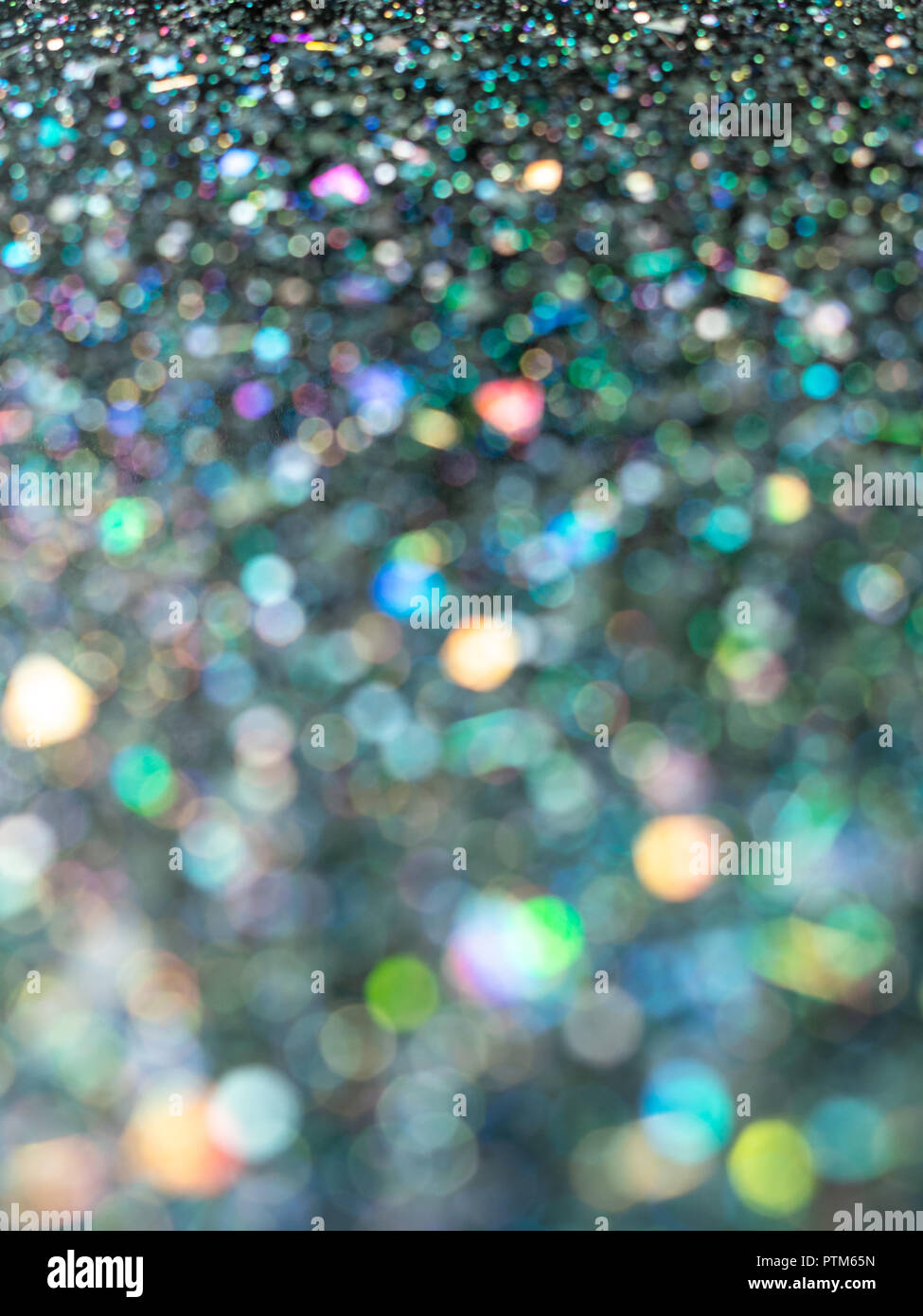 Beautiful bubble and dot bokeh. Blurred Holographic glitter on black background. Abstract art multicolor glitter bokeh background vertical style. Stock Photo