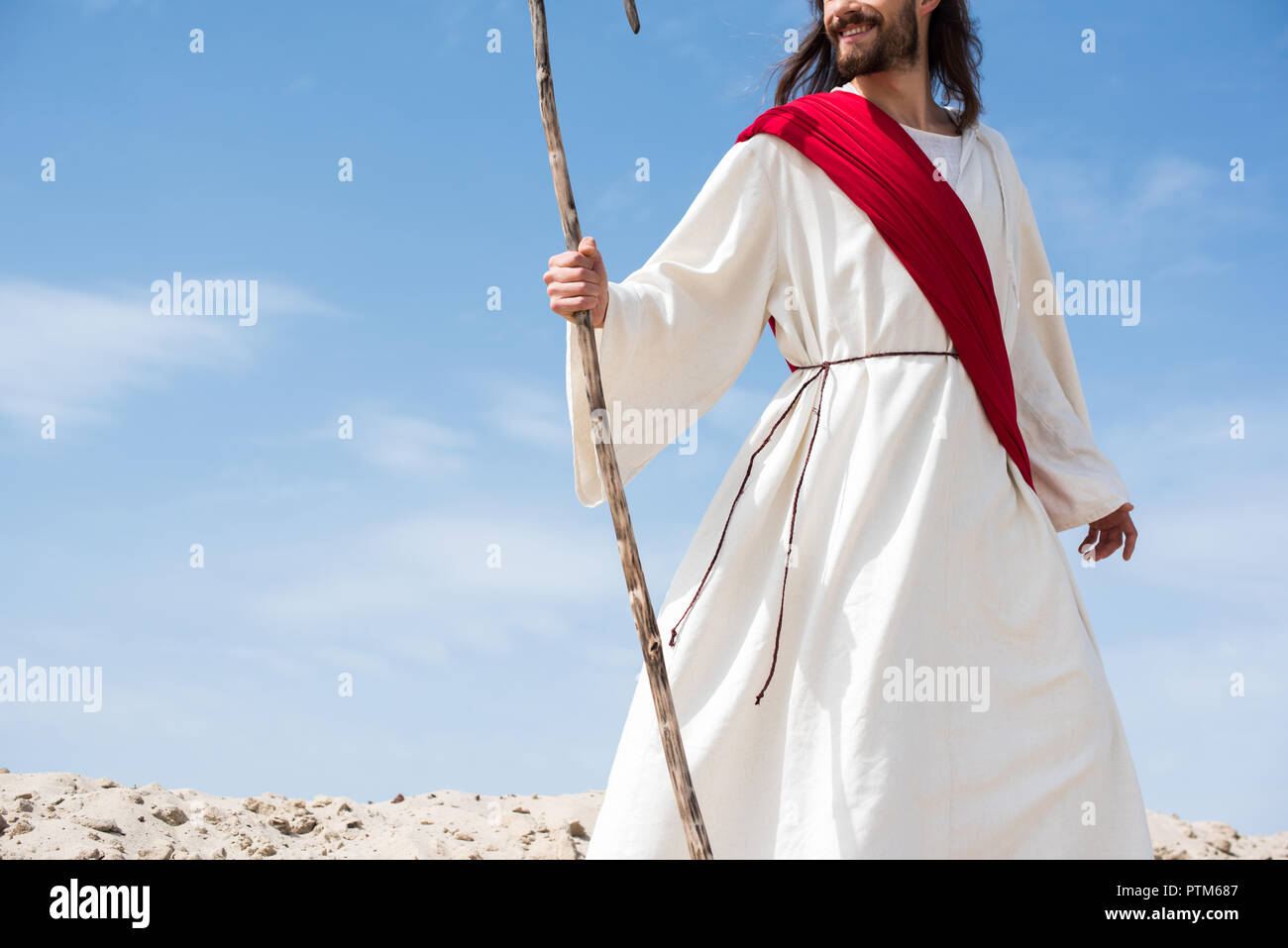 cropped image of smiling Jesus in robe and red sash standing with ...
