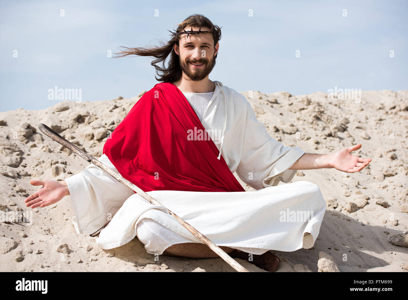 smiling Jesus in robe, red sash and crown of thorns sitting in ...