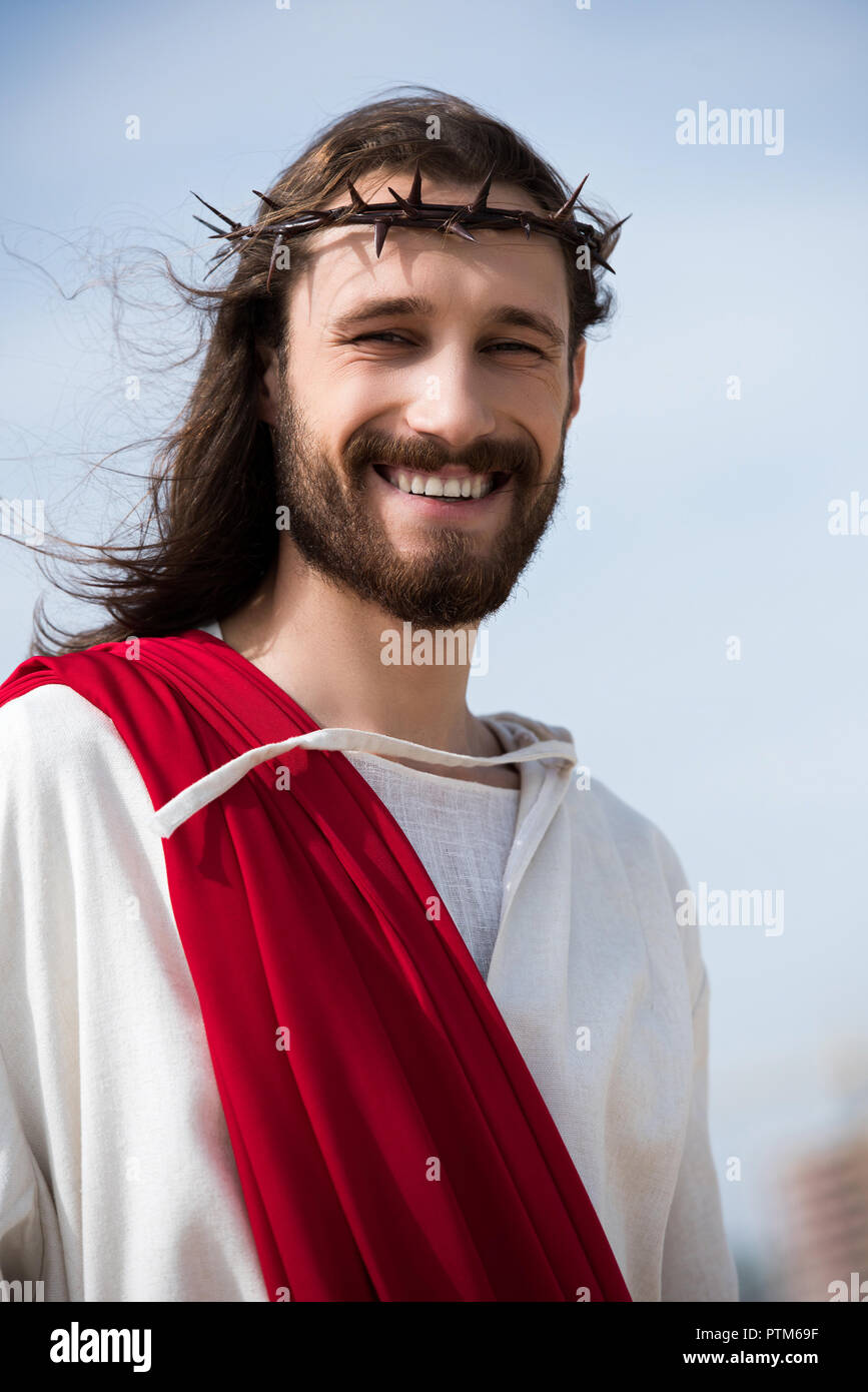 portrait of smiling Jesus in robe, red sash and crown of thorns ...