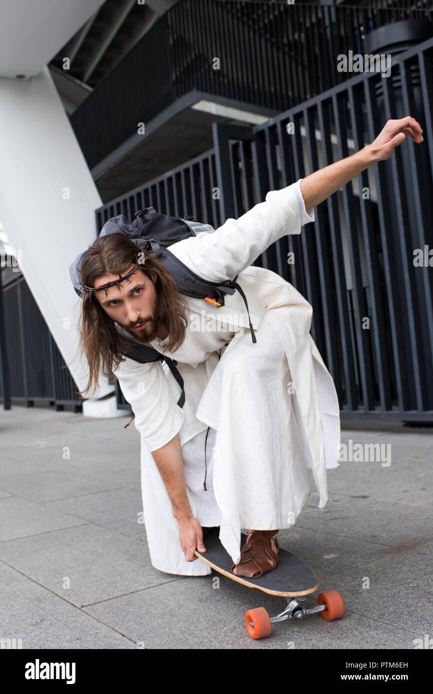 plast Afskrække Massakre handsome Jesus in robe and crown of thorns skating on longboard on street  Stock Photo - Alamy
