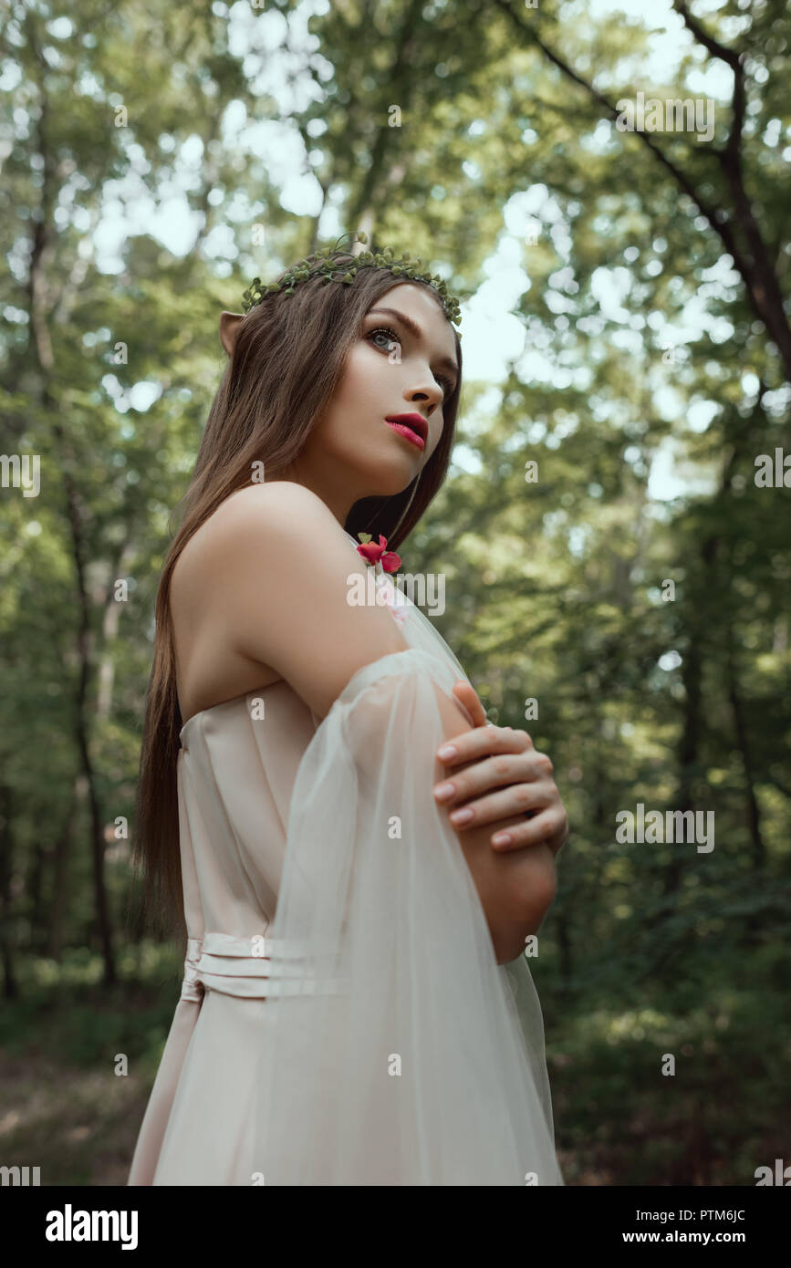 beautiful mystic elf in dress and floral wreath in forest Stock Photo ...