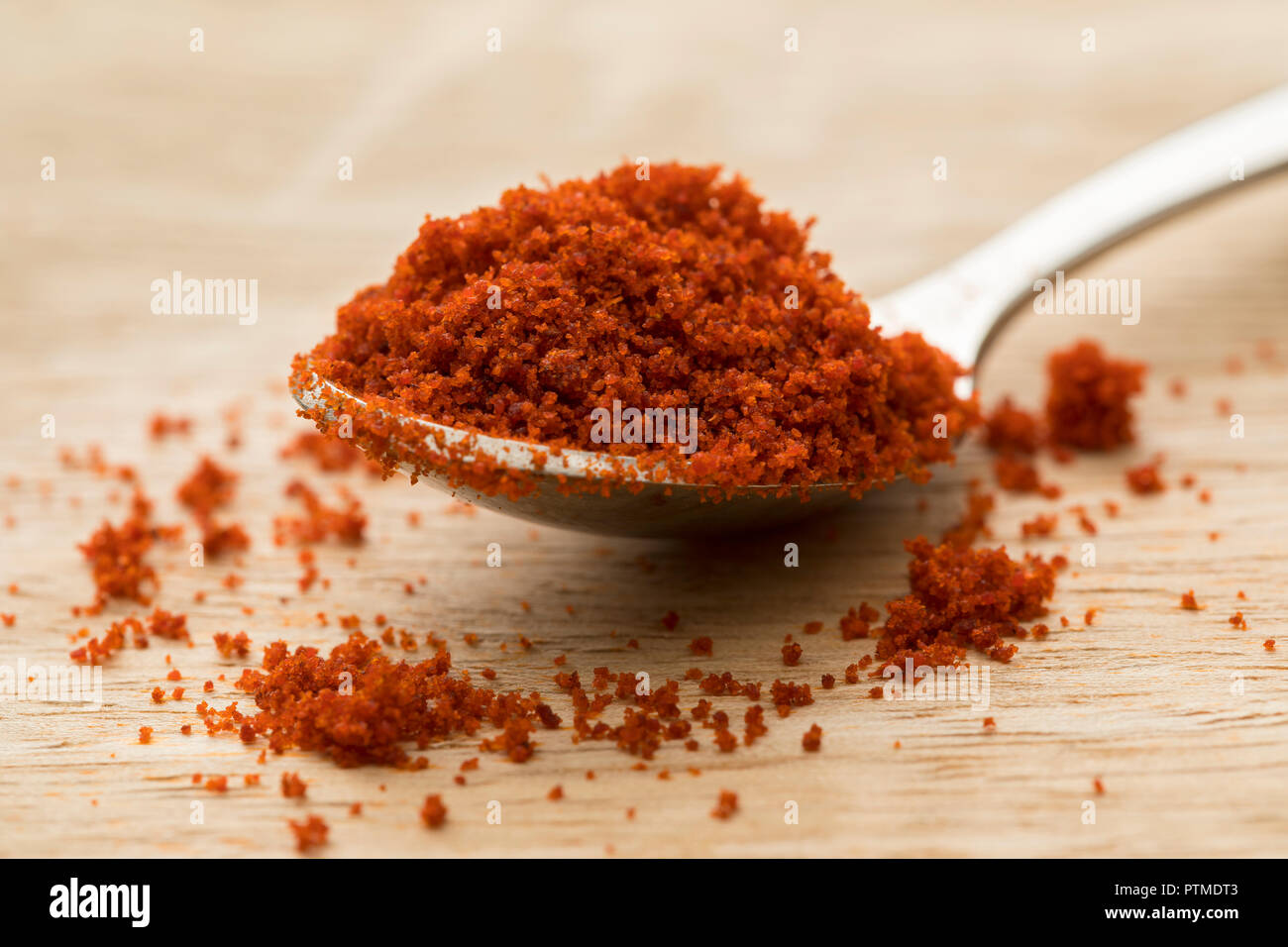 Heap of red paprika powder on a spoon closeup Stock Photo