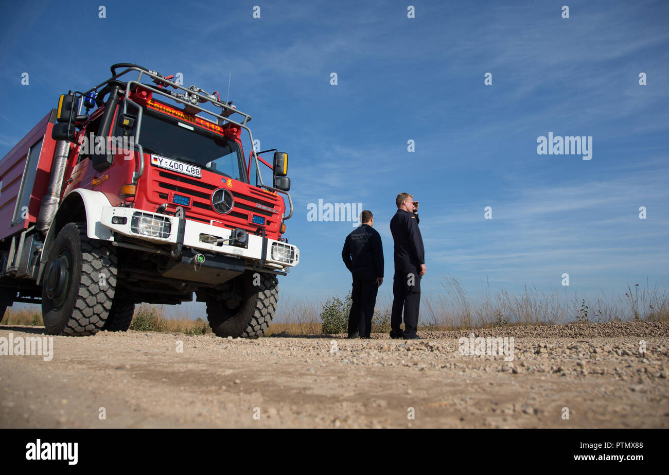 10 October 2018, Lower Saxony, Meppen: 10 October 2018, Germany, Meppen: Fire chief Steffen Voss (L) and senior fire chief Fritz Meinen, of the fire department Bundesfeuerwache Meppen, look at the premises of the Wehrtechnische Dienststelle (WTD) 91. Representatives of the Bundeswehr provide information on the status of fire fighting operations and on the results of various pollutant measurements. In September, five hectares of moorland had caught fire on a Bundeswehr test site. Photo: Friso Gentsch/dpa Stock Photo