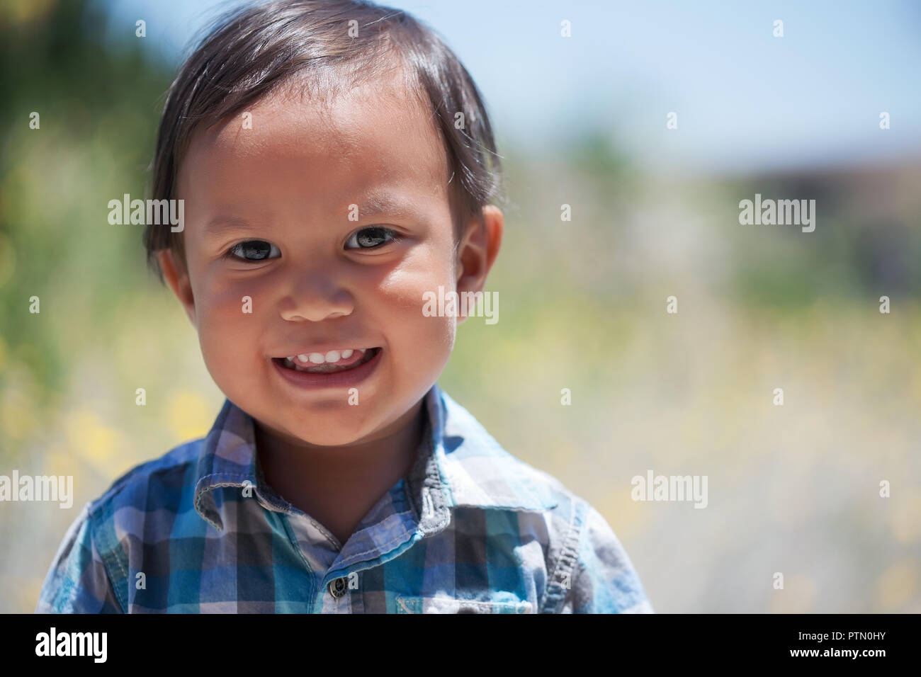 Smiling boy 2 year old wearing plaid shirt outdoors on a sunny summer day looking healthy and happy Stock Photo