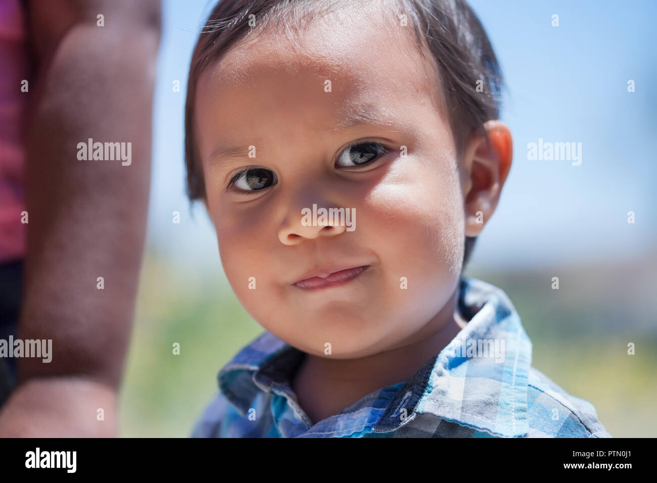 Smart 2 year old boy with bright eyes and cute smile looking innocent and standing next to sister in an outdoor park during summer Stock Photo