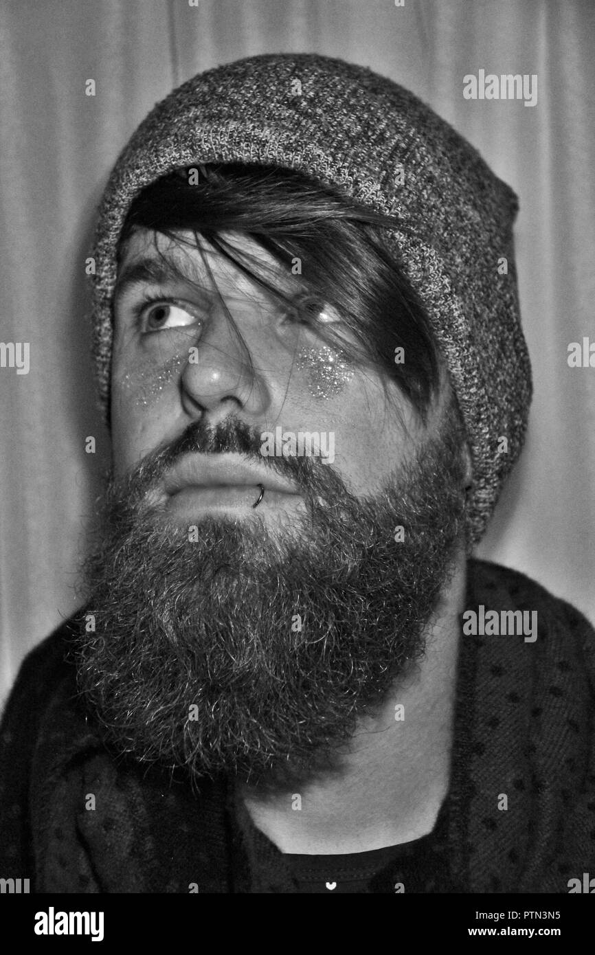 Bearded man, looking away. Beard, surf, piercing, smile. Stock Photo