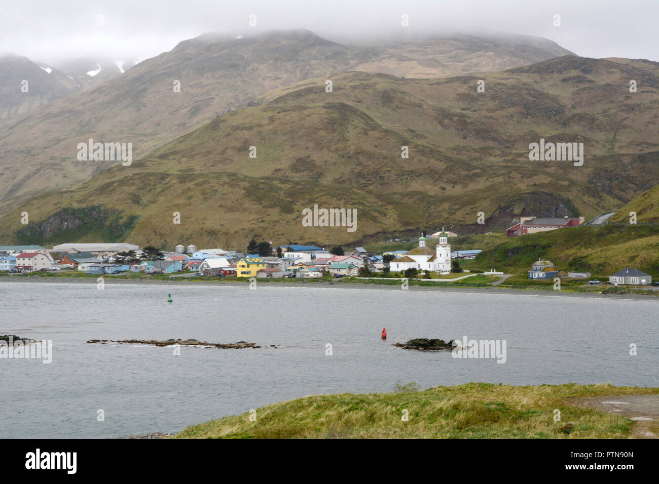 The city of Unalaska, also known as Dutch Harbor, surrounded by mountains and the Bering Sea, on Unalaska Island, Aleutian archipelago, Alaska. Stock Photo