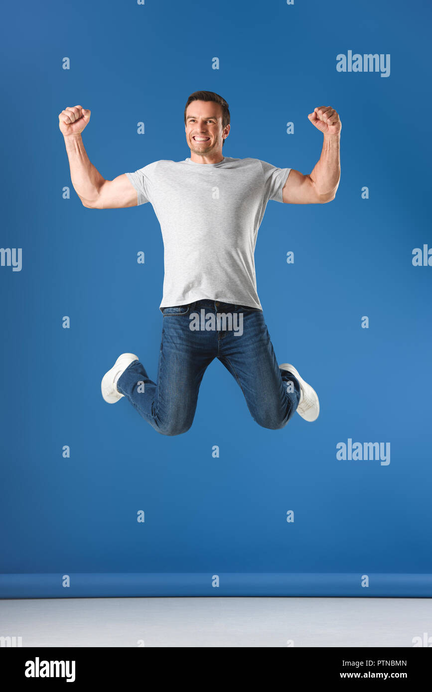 excited man jumping and triumphing on blue Stock Photo