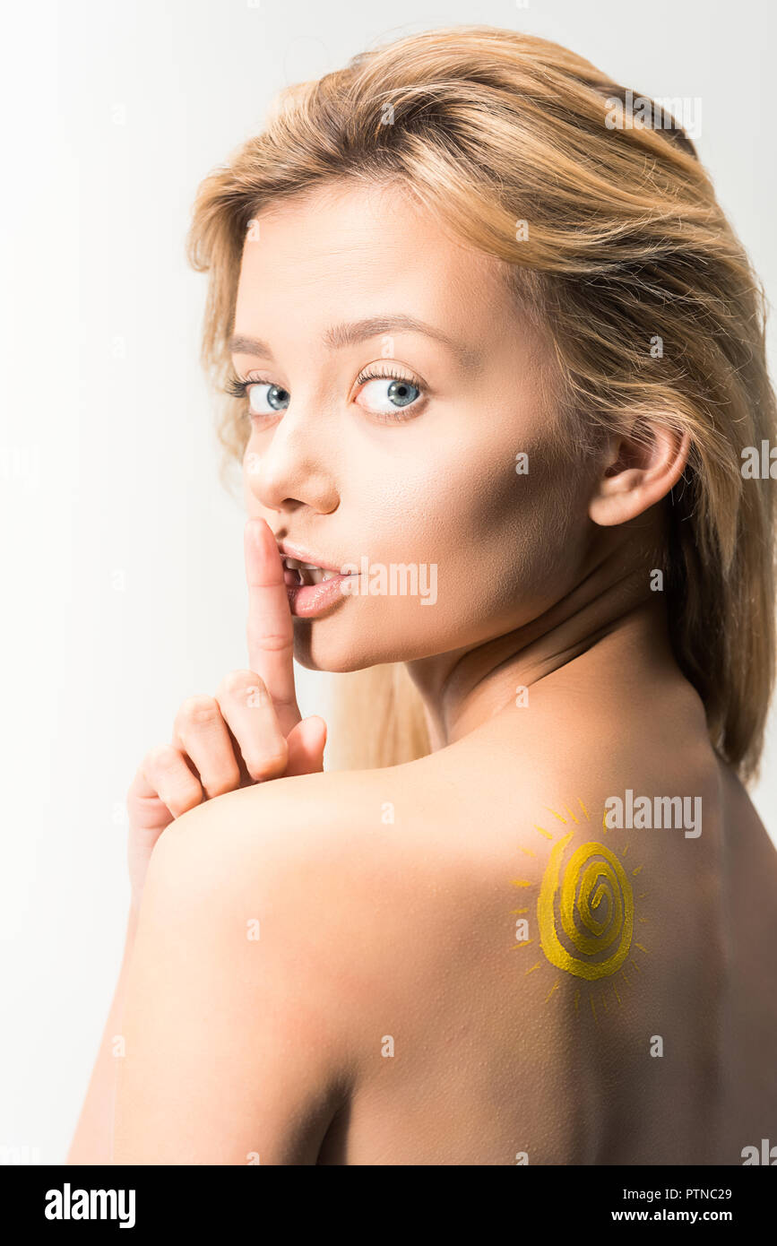 beautiful girl with painted yellow sun on shoulder showing silence gesture isolated on white Stock Photo