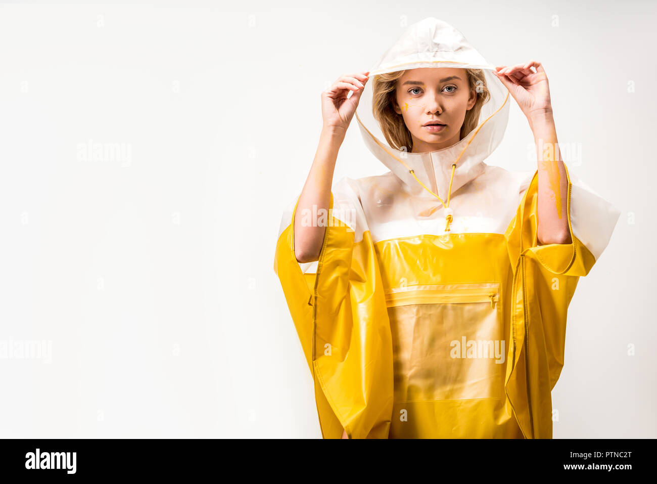 beautiful woman in raincoat holding hood and looking at camera isolated ...