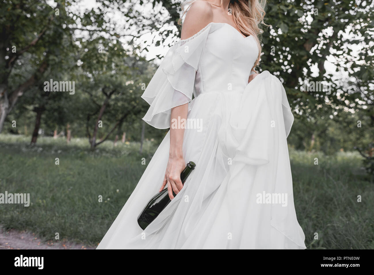 Cropped Shot Of Young Bride In Wedding Dress Holding Bottle Of