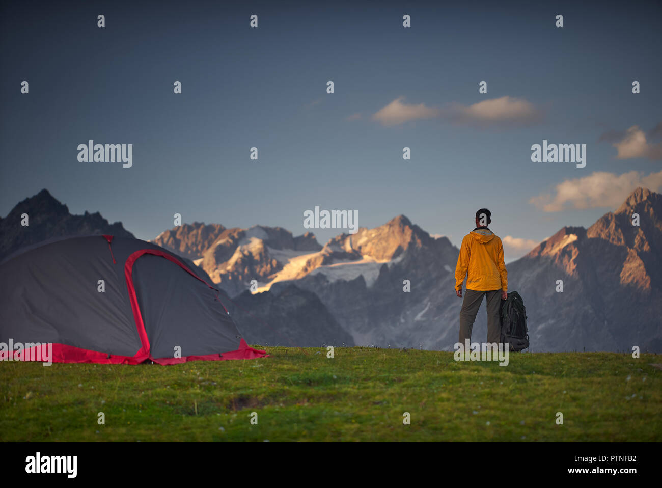 Hiker in a camp and looking at mountains in a sumer day. Stock Photo