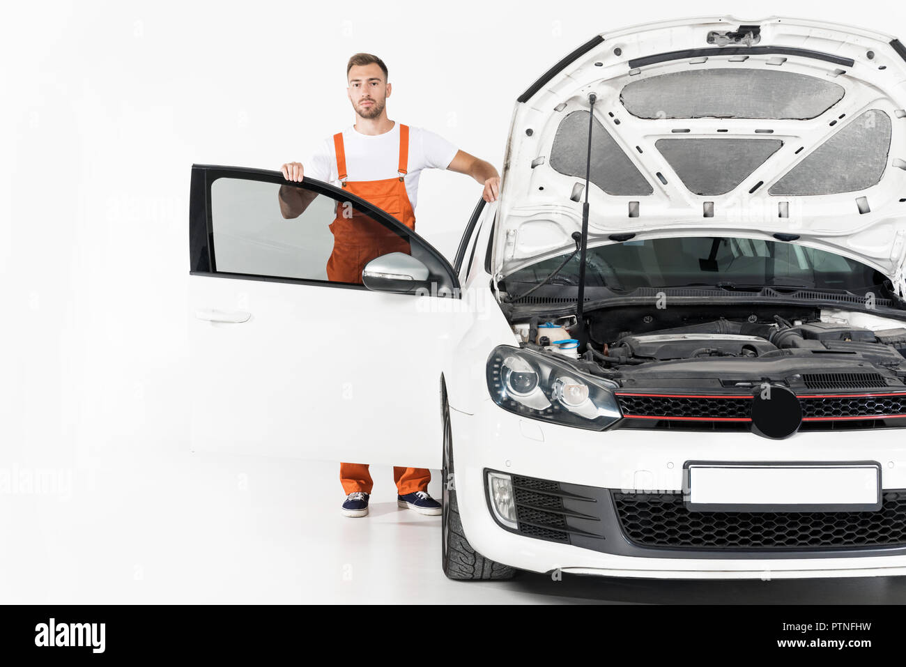 handsome auto mechanic standing near car with open hood and door on