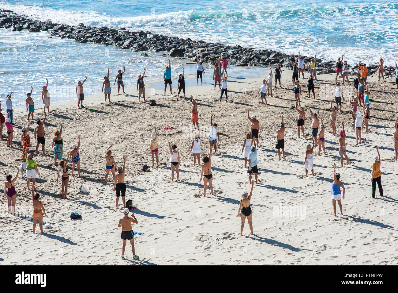 A group of beautiful people enjoying and practicing Qigong on the beach near Barcelona. Vilanova i la Geltru' 2018 Stock Photo