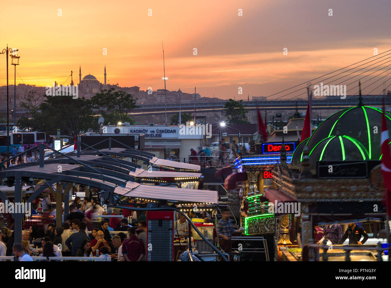 Eminonu outdoor restaurants with diners and mosque at sunset, Istanbul
