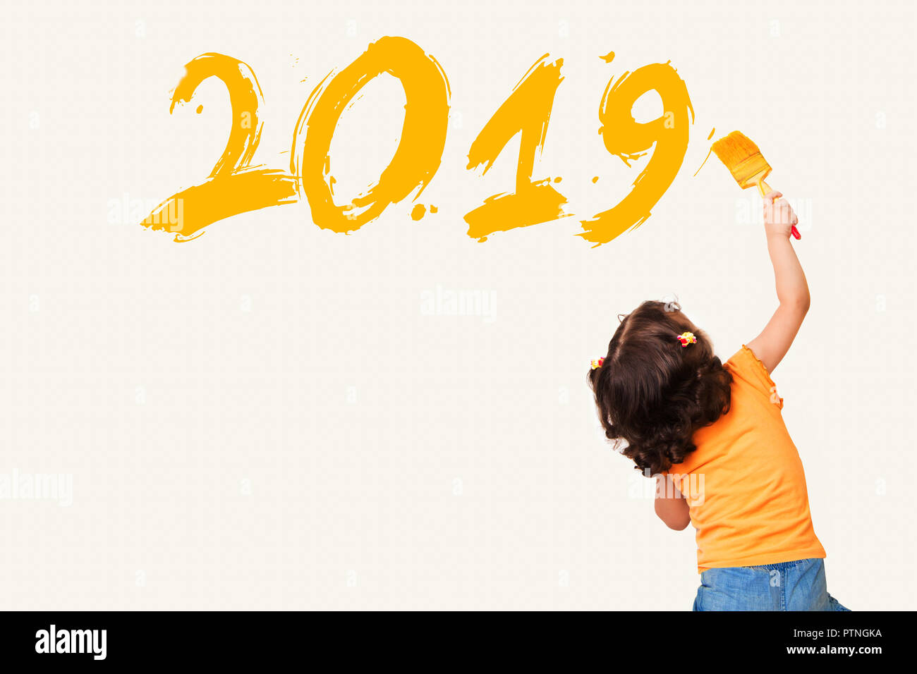 Cute little girl drawing new year 2019 with painting brush on wall