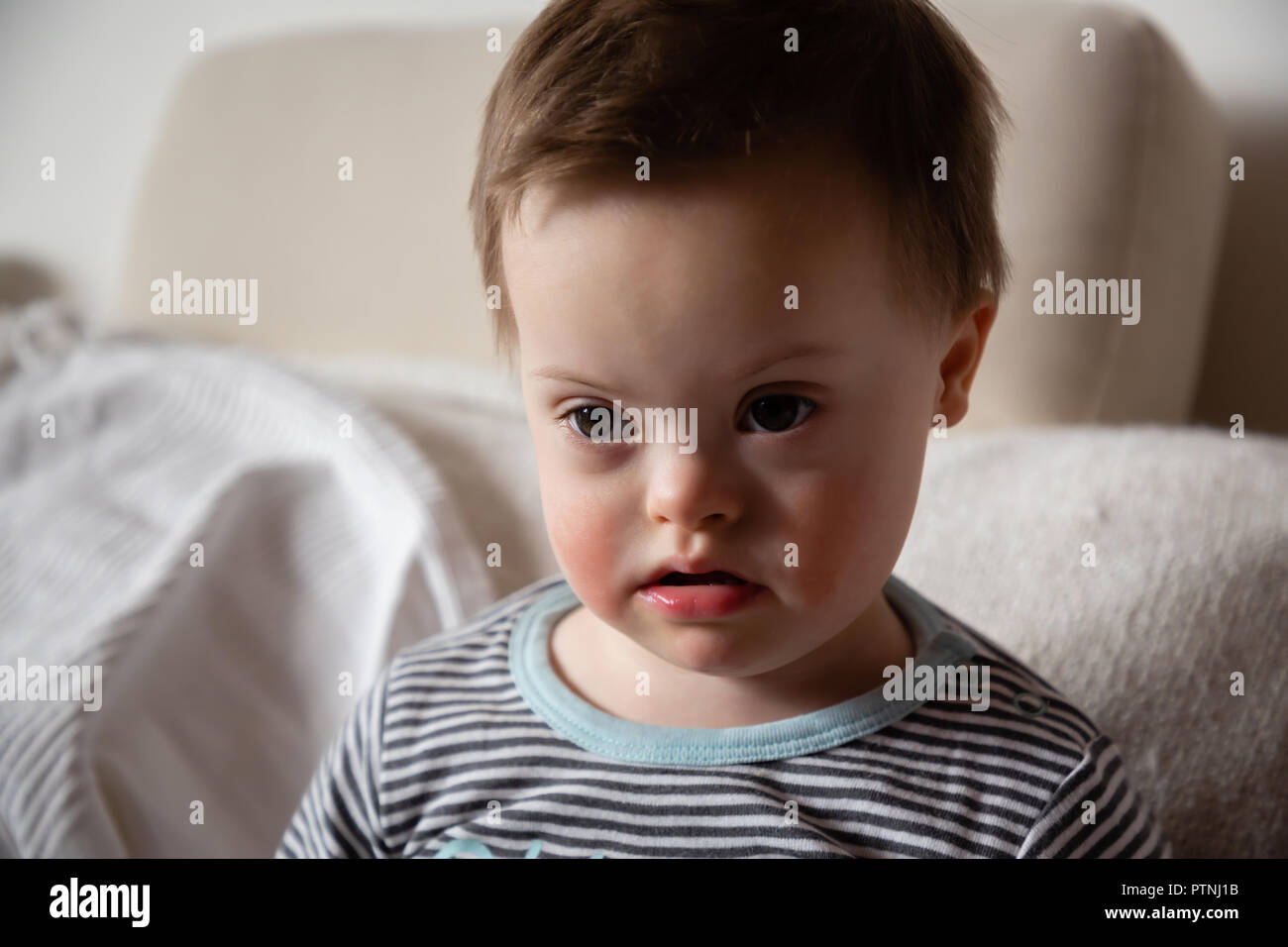 Portrait of cute small boy with Down syndrome in home Stock Photo